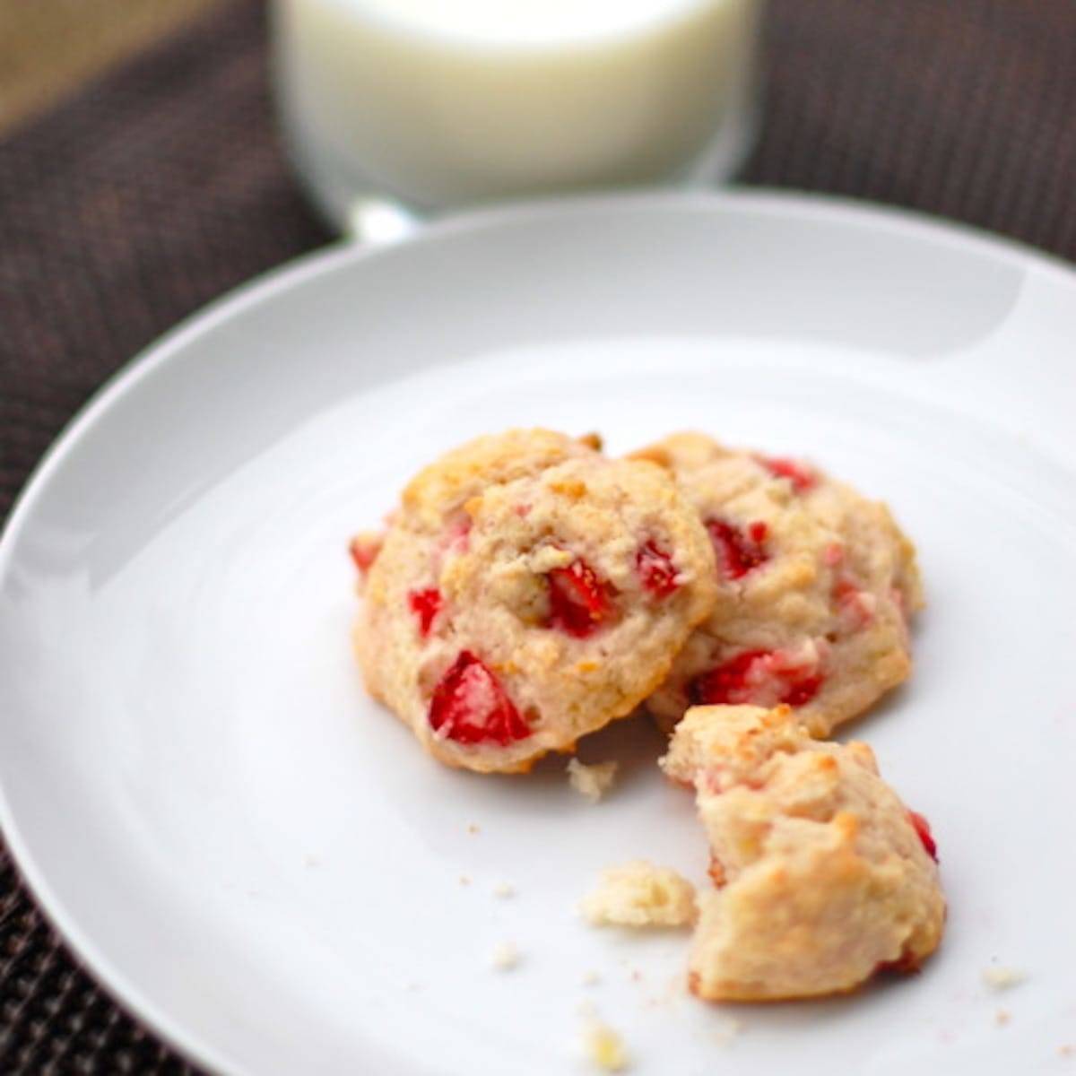 Three orangeberry shortcake cookies on a white plate with crumbles.