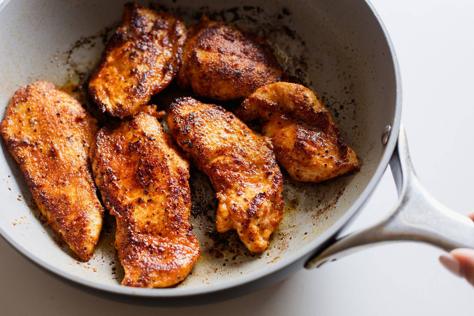 Cooked spiced chicken in a sauté pan.