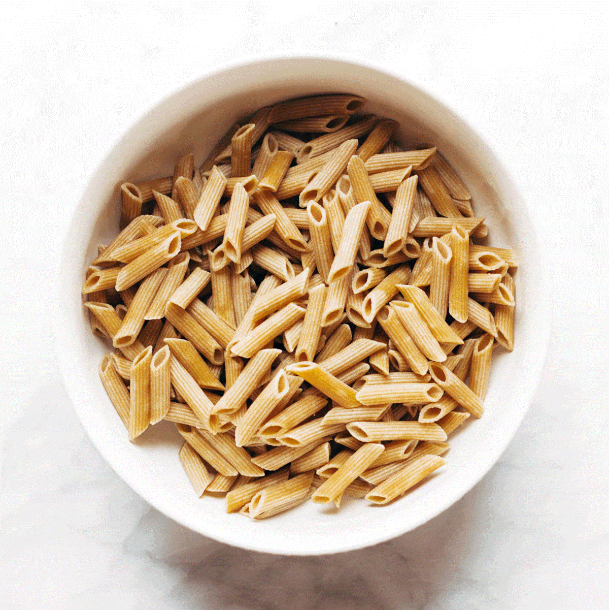 Dry penne noodles in a bowl.