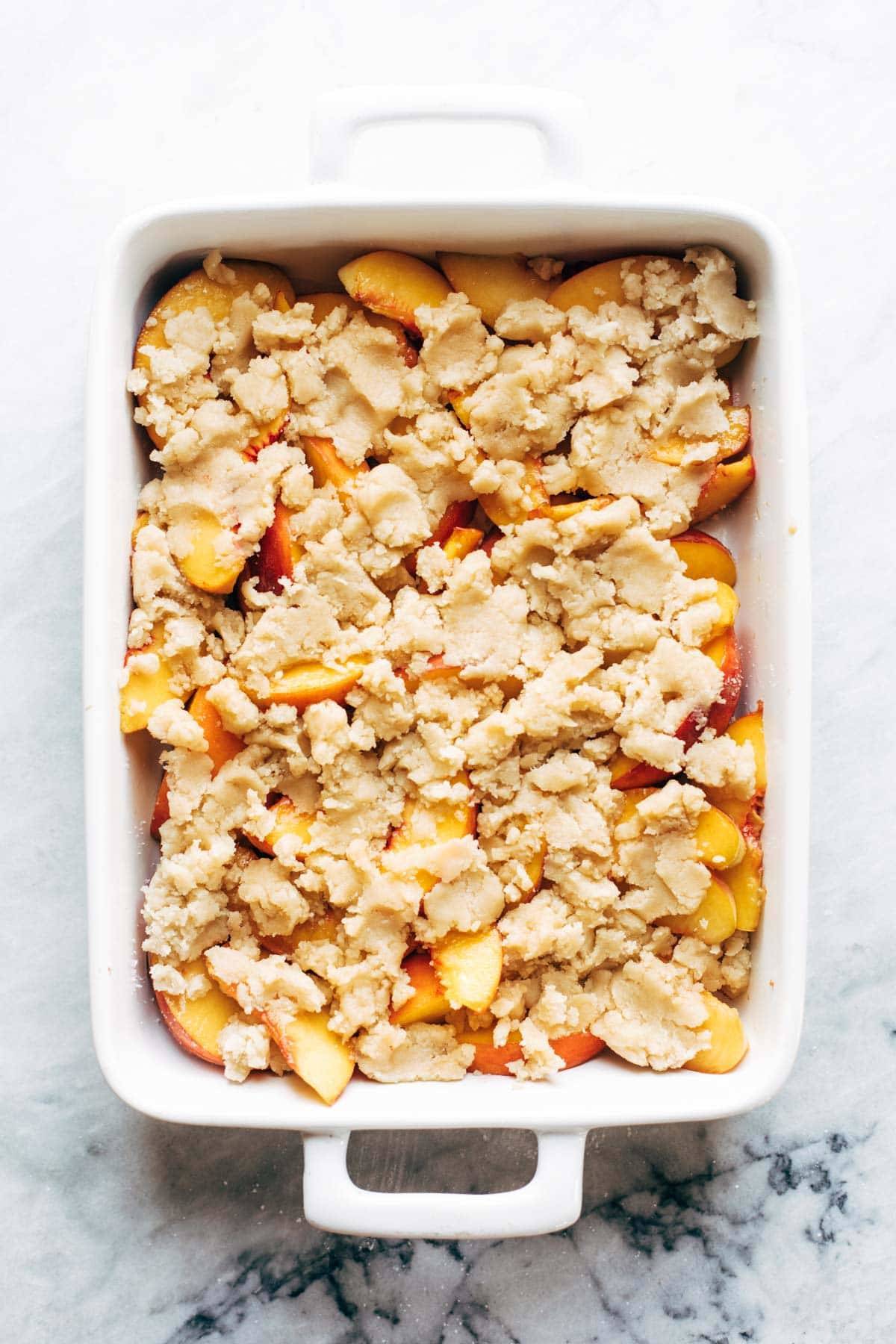 Peach cobbler assembled in a dish and ready to be baked. 