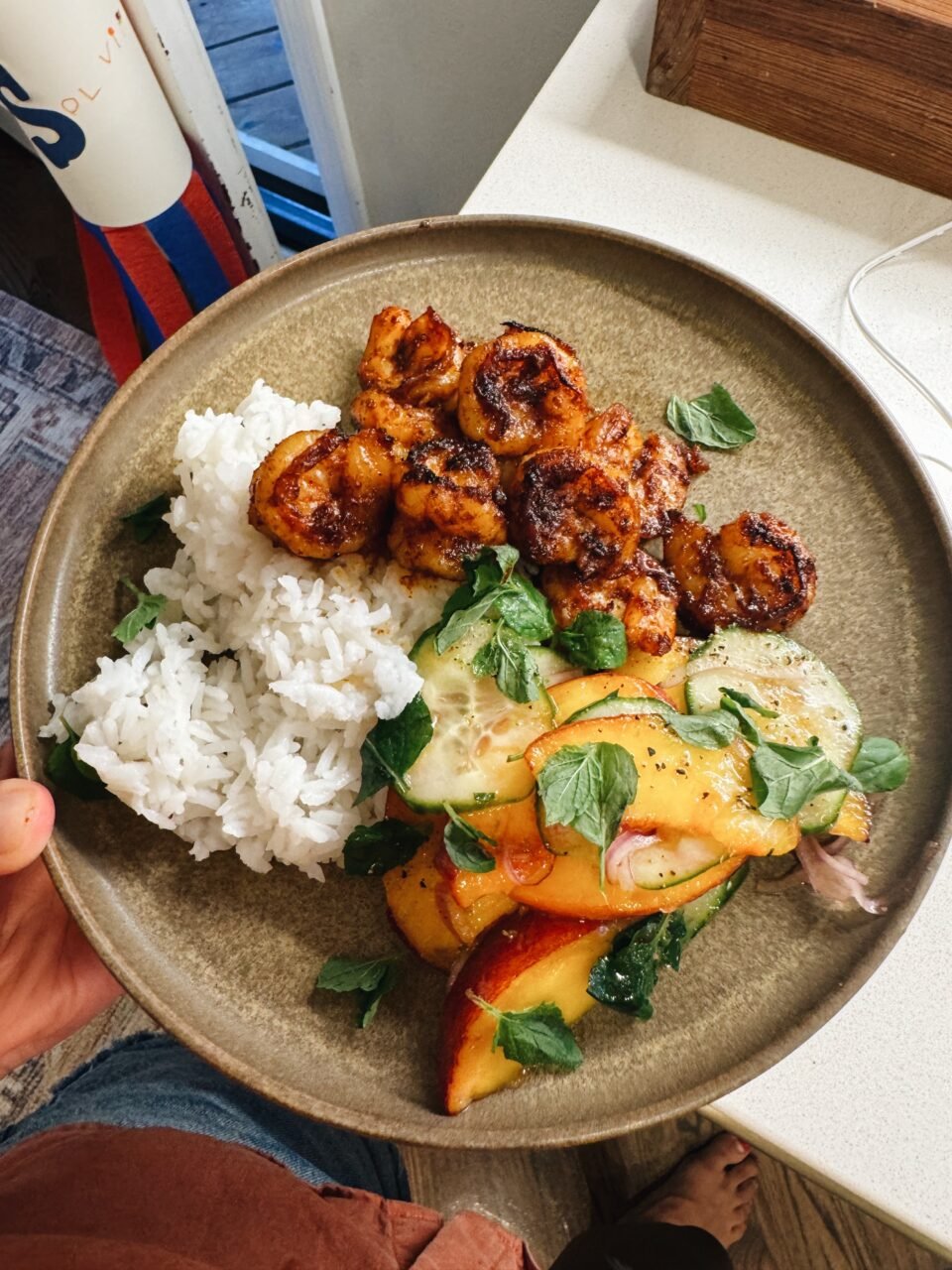 A dinner plate with rice, spicy shrimp, and peach salad.