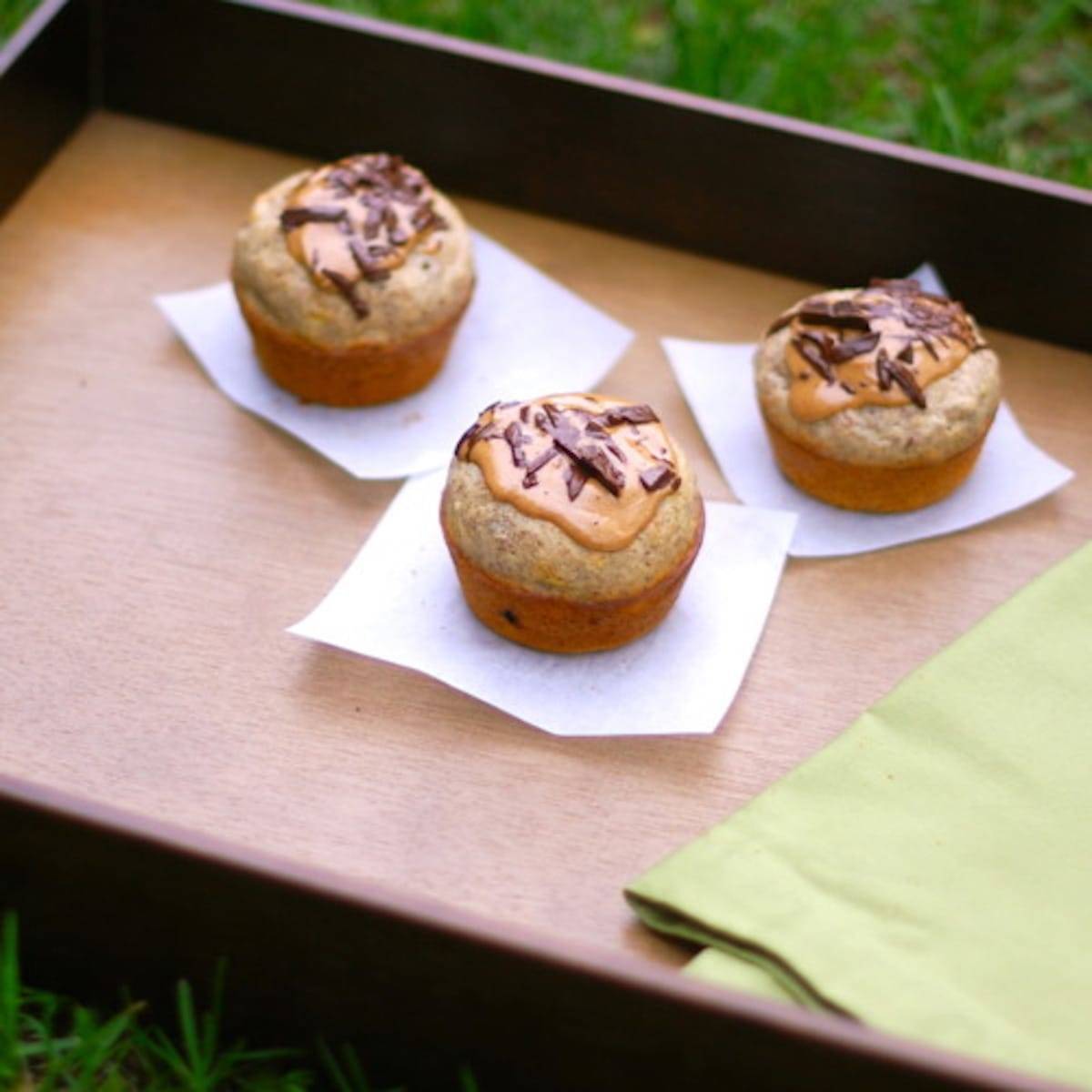 Three peanut butter banana flax muffins on parchment paper.