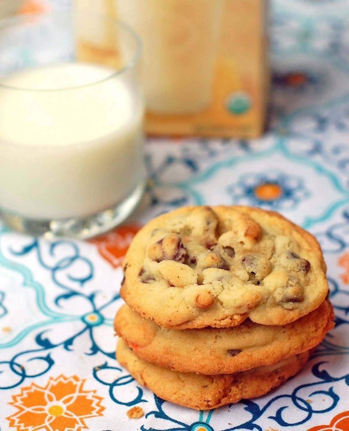 Peanut butter pretzel cookies stacked on each other next to a glass of milk.