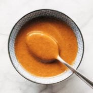 Creamy peanut sauce in a bowl with a spoon.