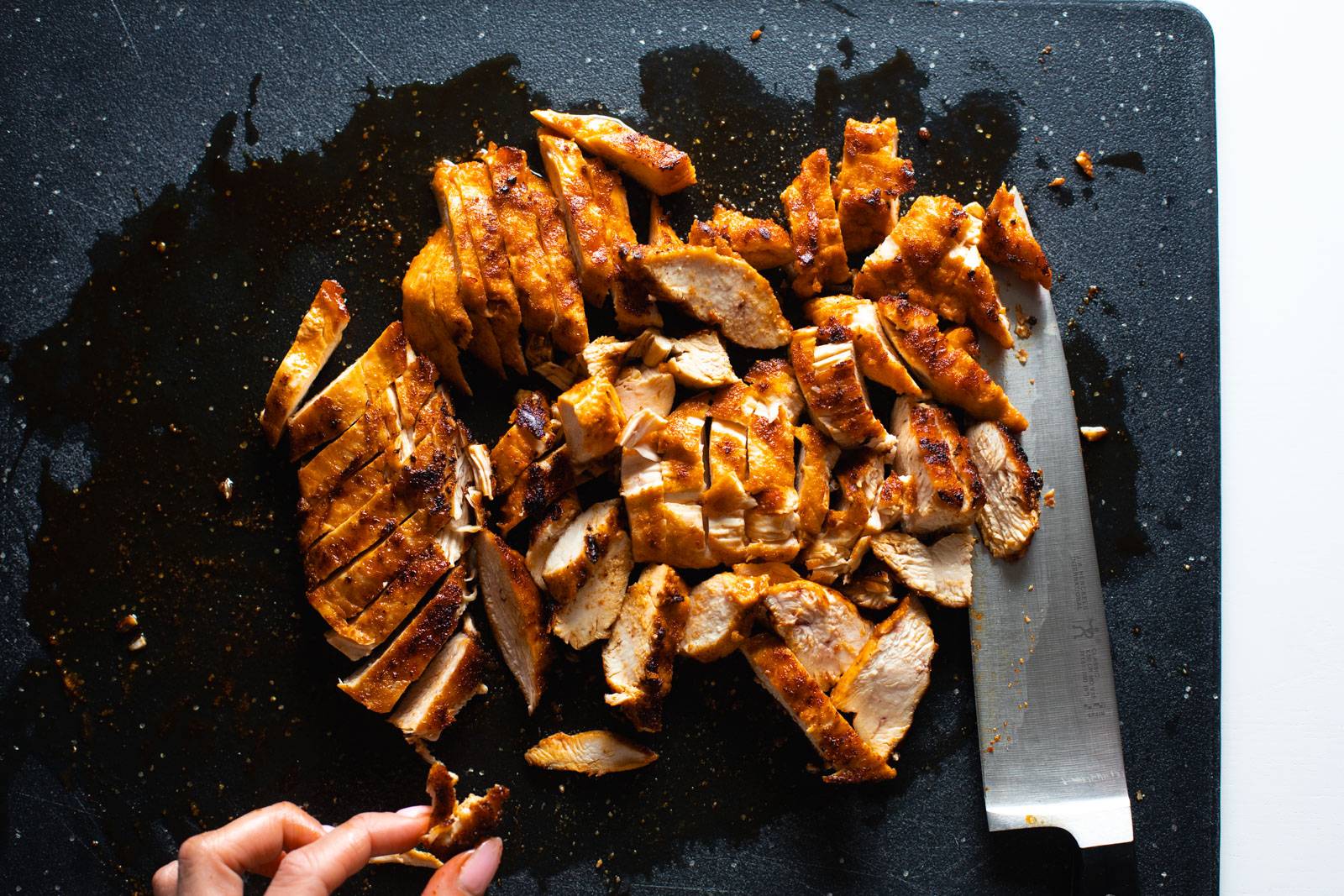 Grilled chicken chopped up on a cutting board