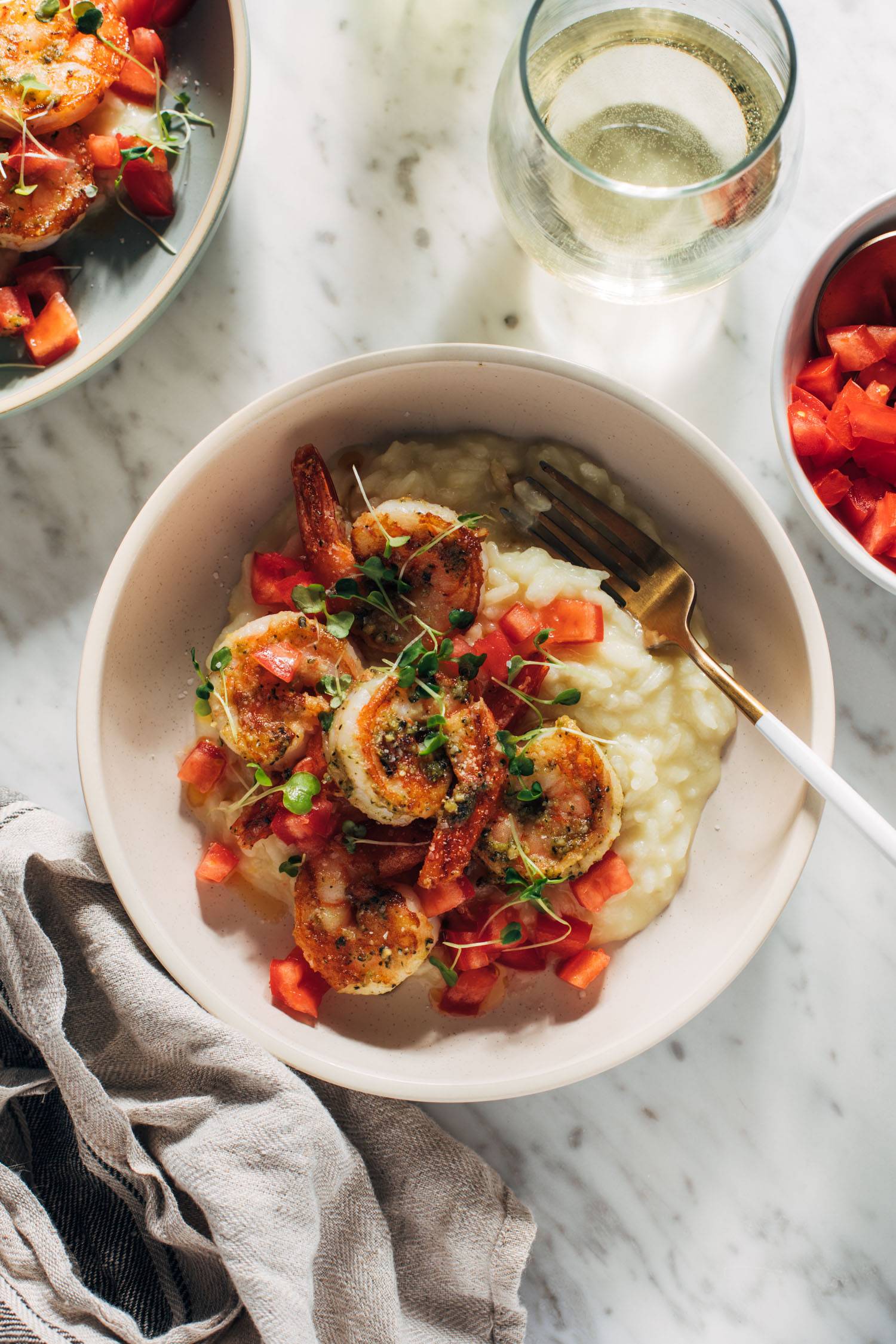 Crevettes nuisibles dans un bol avec du risotto et une fourchette et un verre de vin blanc sur le côté