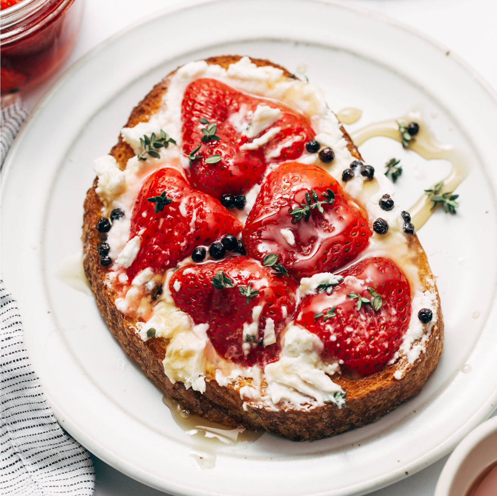 Pickled strawberries on a piece of toast with creamy cheese.