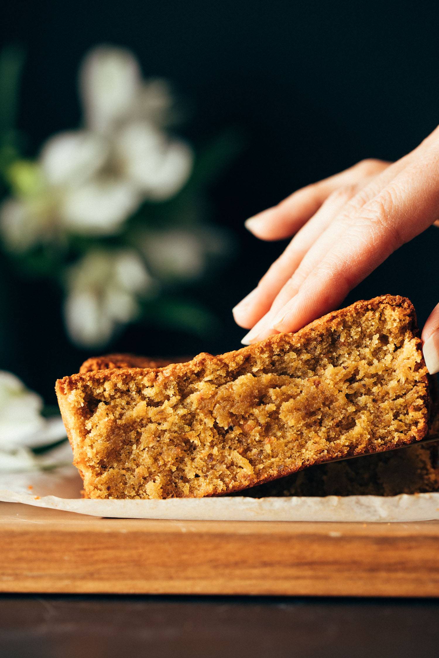 Hand grabbing slice of pistachio loaf.