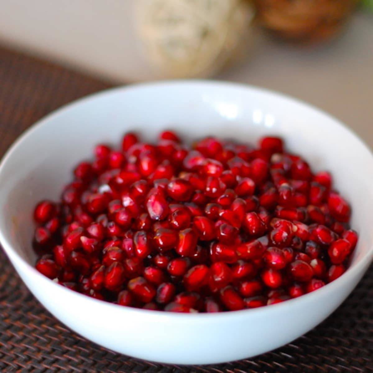 Pomegranate seeds for muffins in a white bowl.