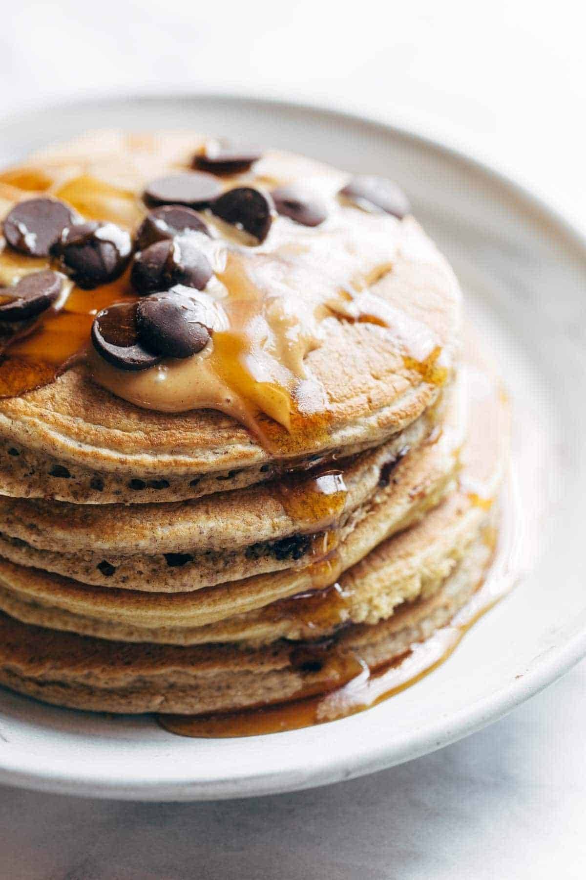 pancakes on a plate with peanut butter, syrup, and chocolate chips