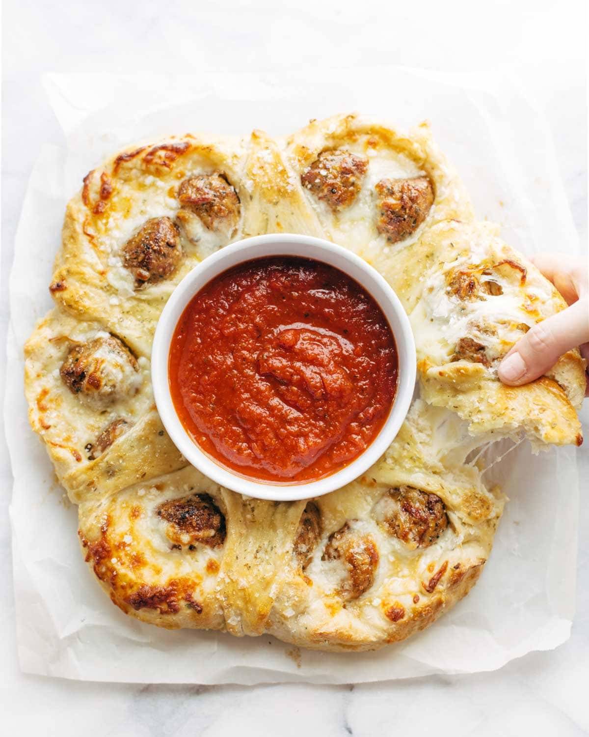 Cheesy Meatball Pull-Apart Pizza Ring with a bowl of marinara sauce