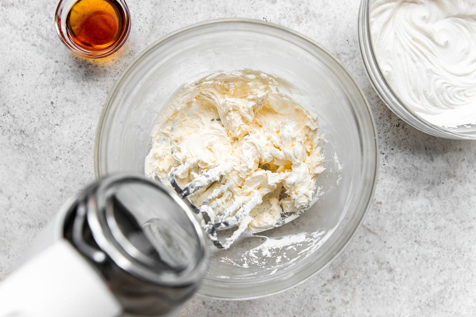 Whipping together the cream cheese whipped cream in a bowl with an electric mixer.
