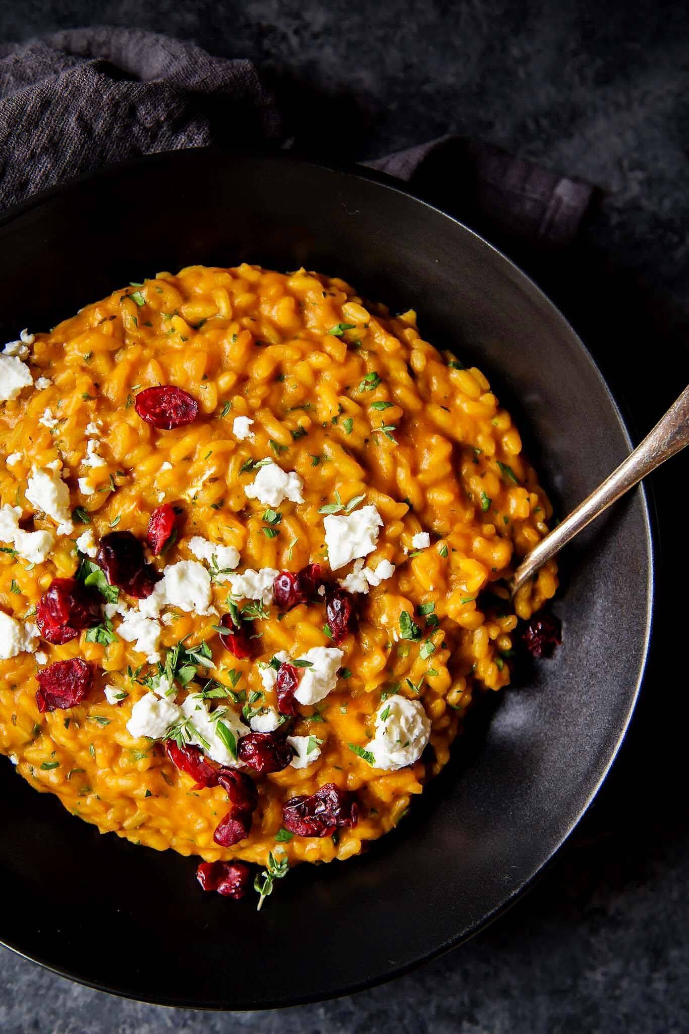 Pumpkin risotto in a bowl with a spoon in it.