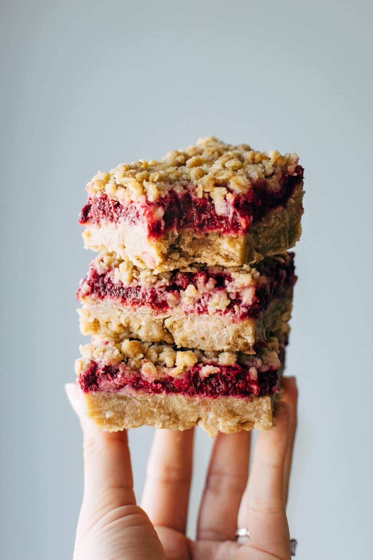 Raspberry Crumble Bars stacked on hand.