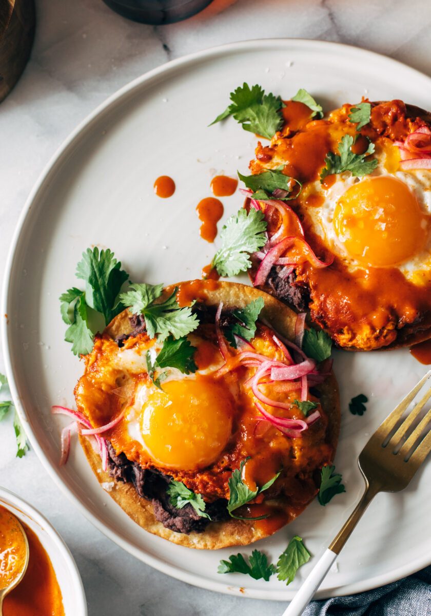 Red chile tostadas on a plate with eggs and a gold fork.