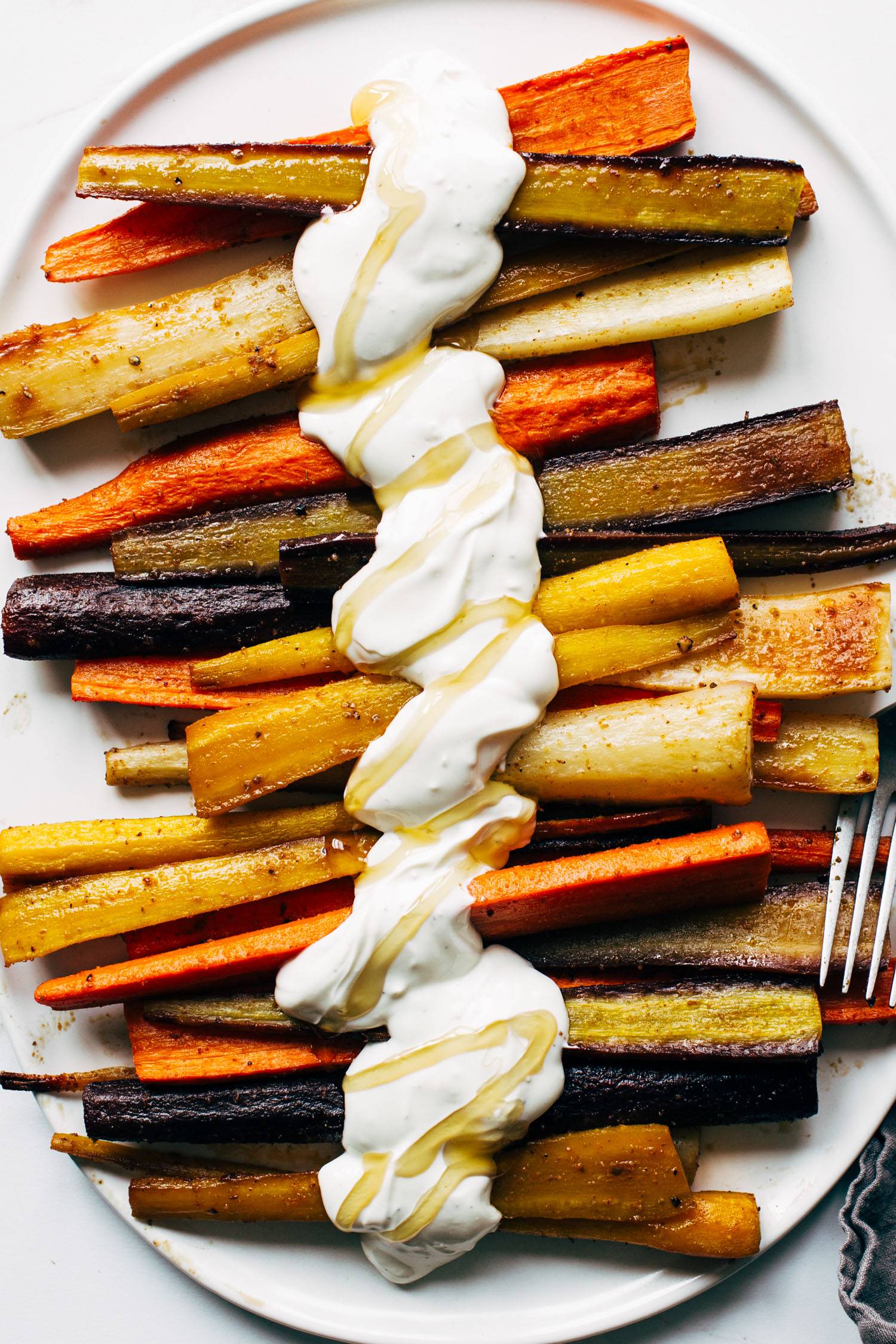 Roasted carrots on a plate with yogurt sauce and honey.