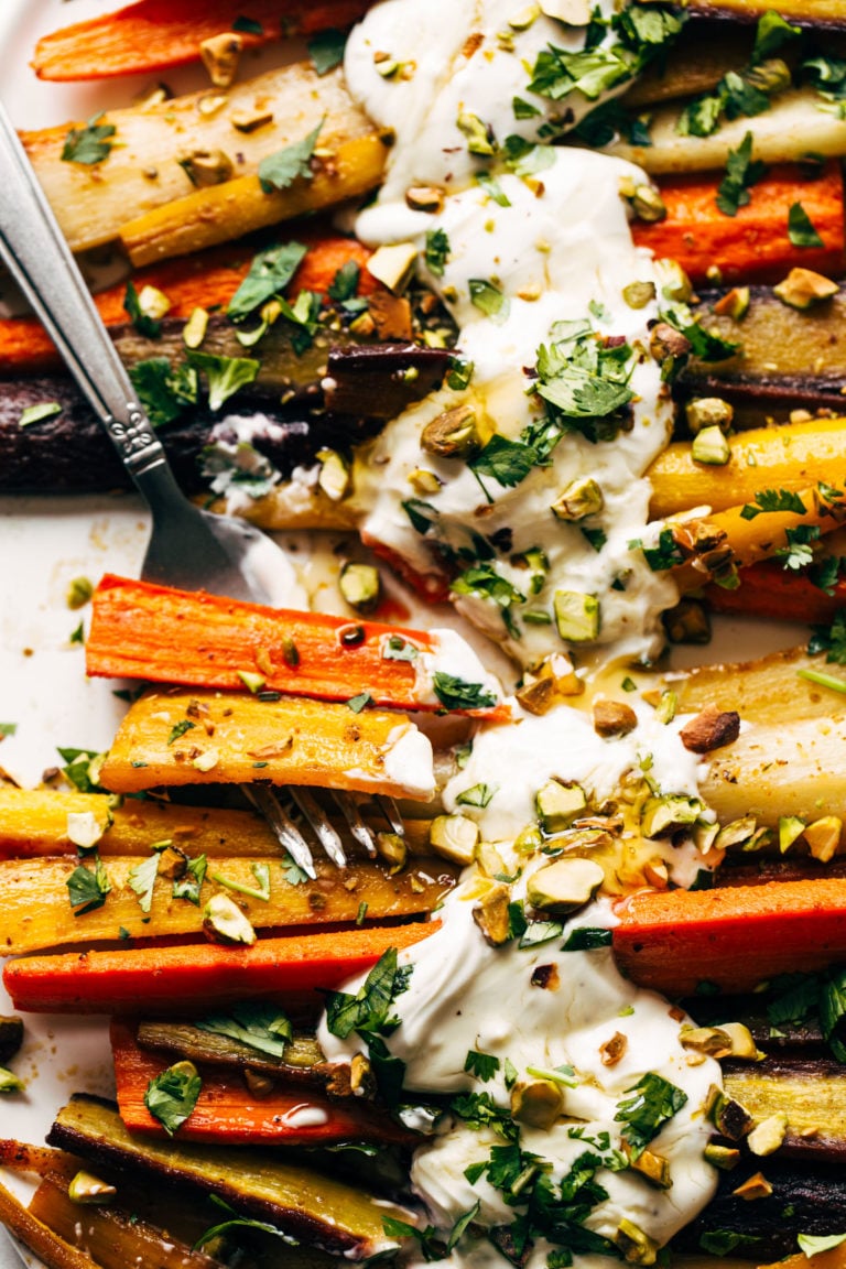 Heirloom carrots on a sheet pan with yogurt sauce and a fork.