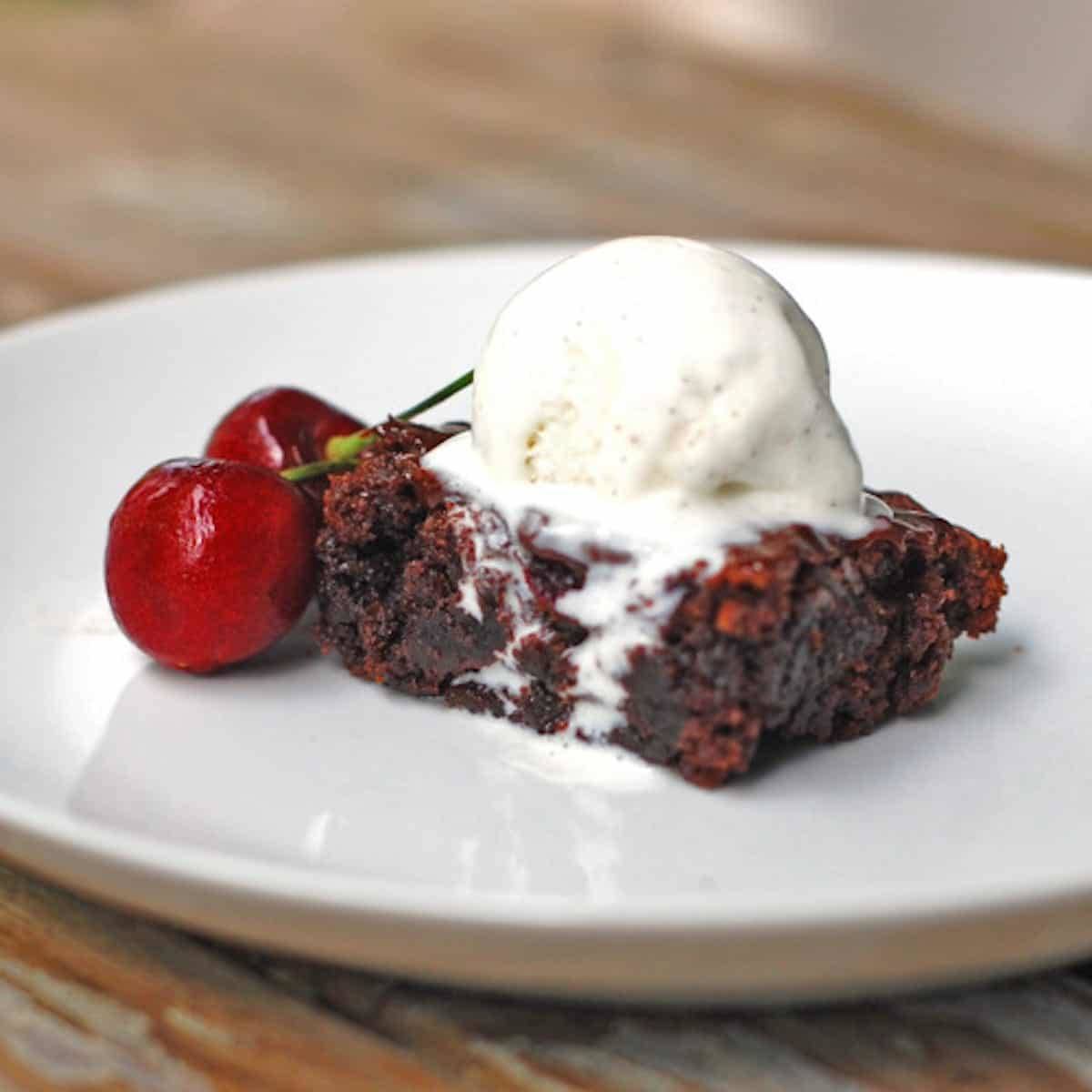 Roasted cherry brownie on a plate with ice cream.