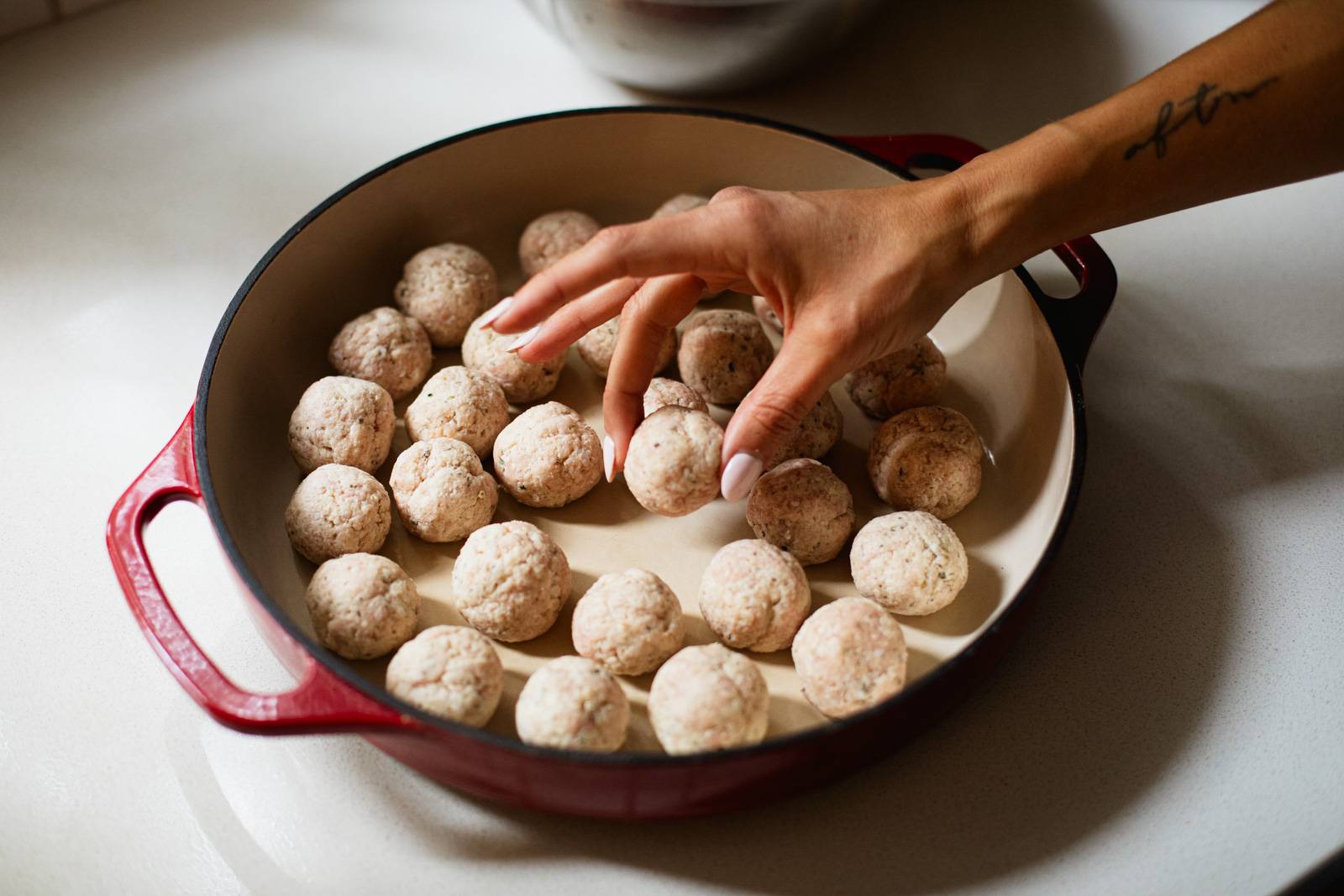 Placing meatballs in a bowl before cooking.