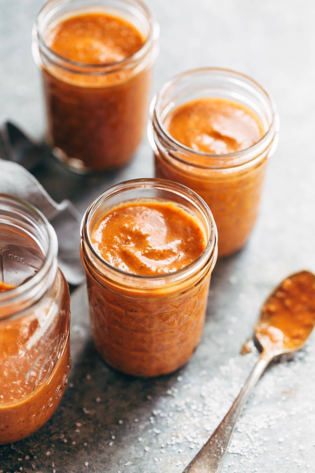 Romesco sauce in jars with a spoon.