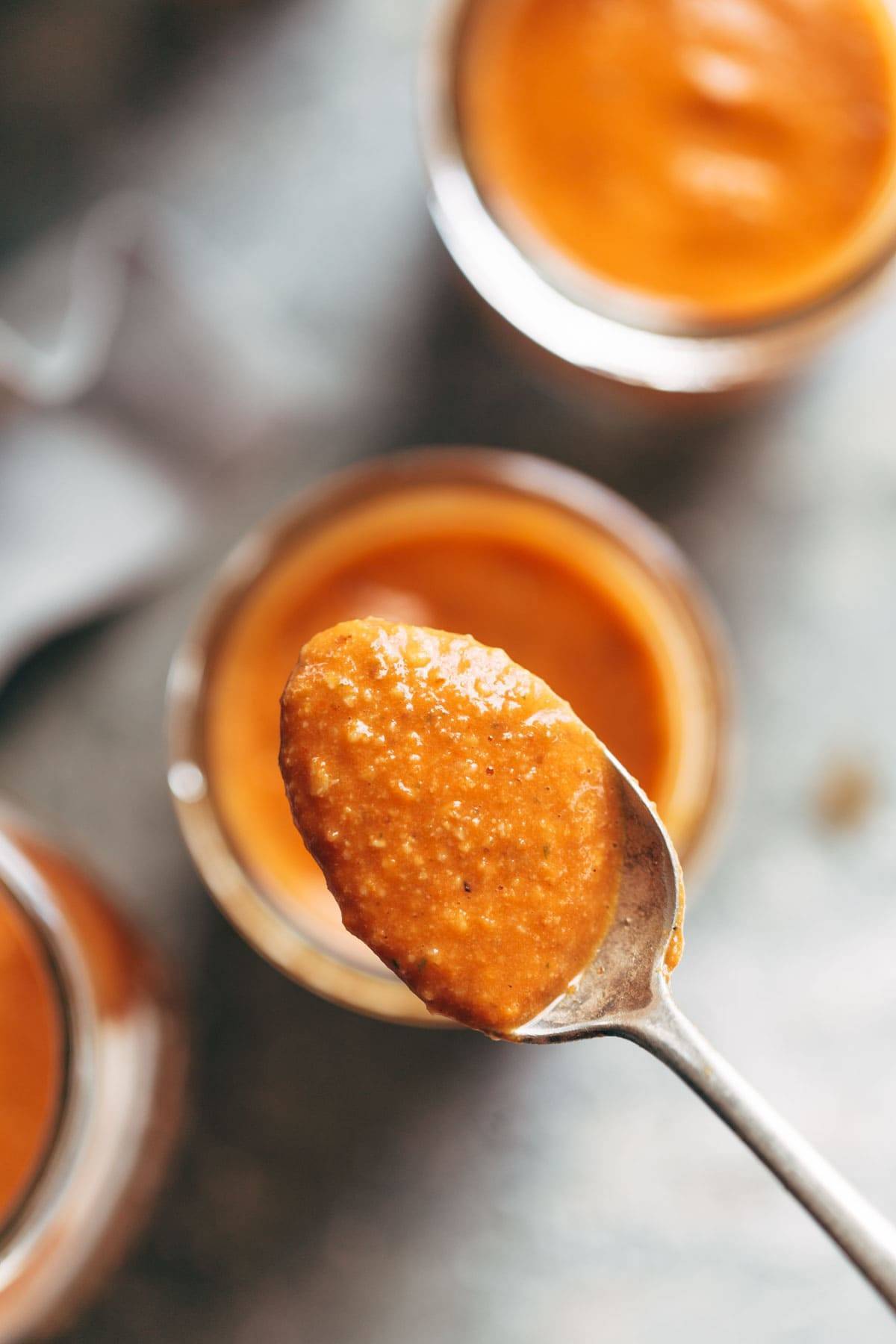 Romesco Sauce in a jar with a spoon.
