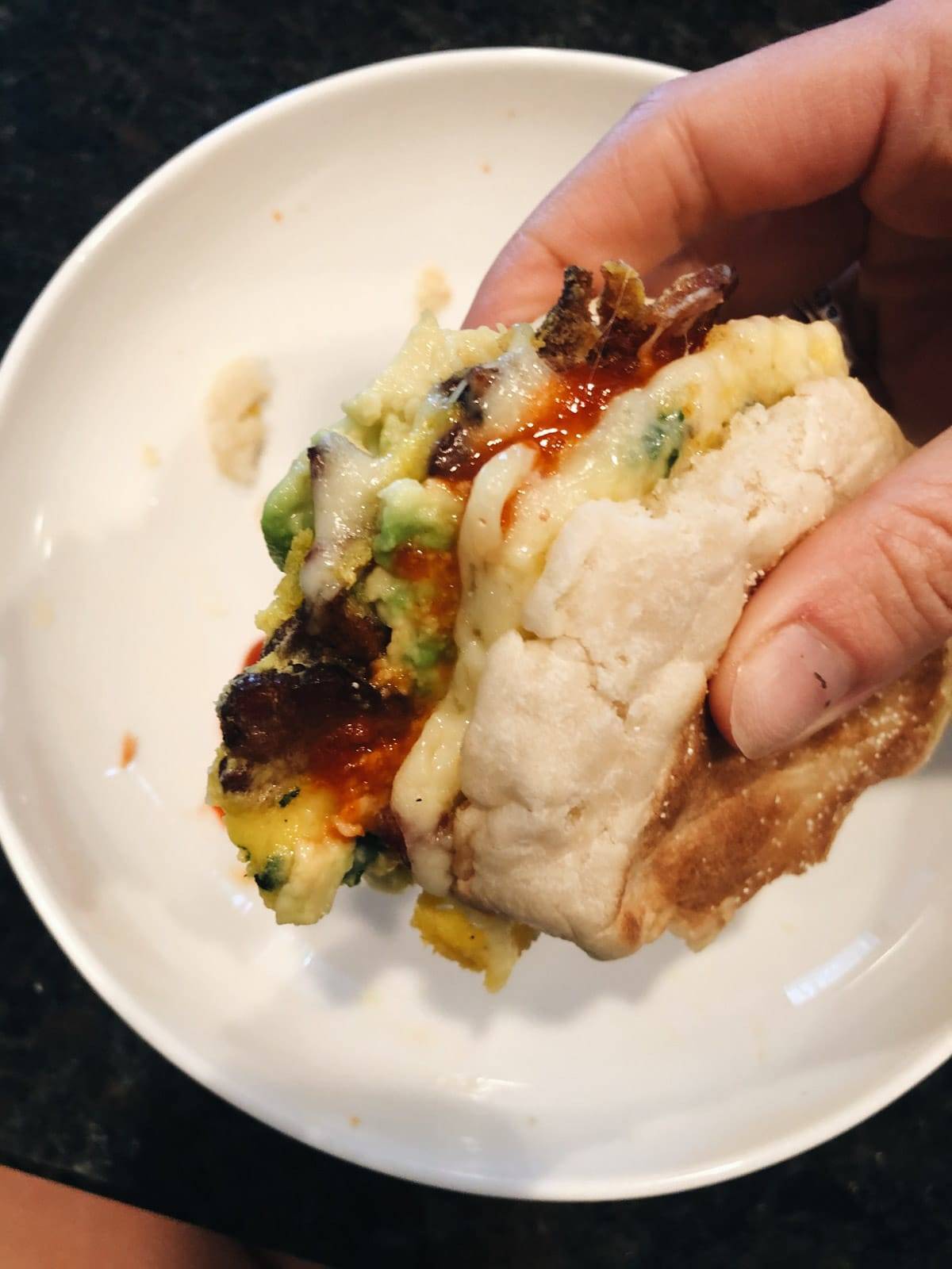 A hand holding a meal prep breakfast sandwich.