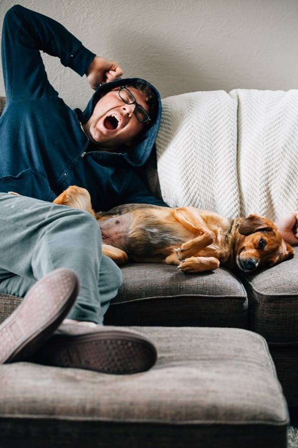 Man yawning and laying with a dog.