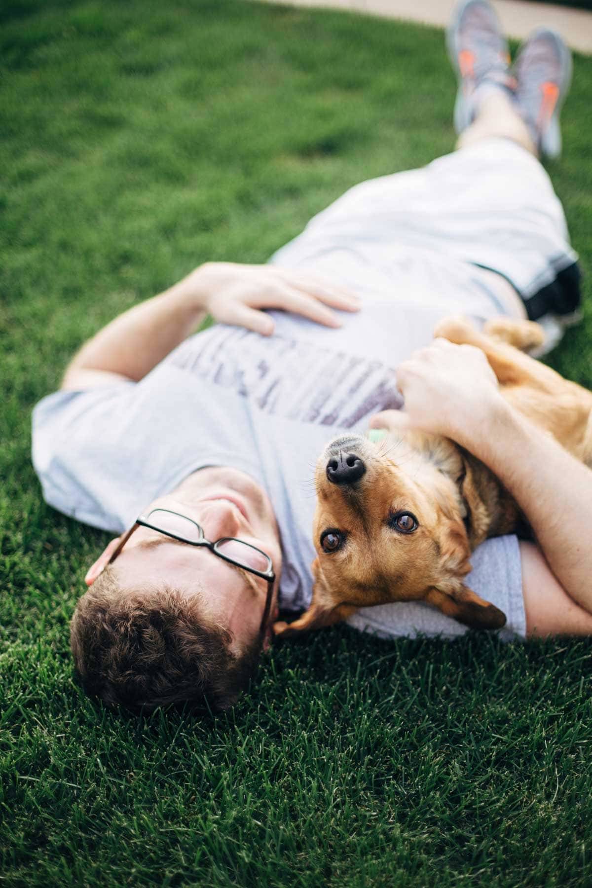 Man and dog laying in the grass.