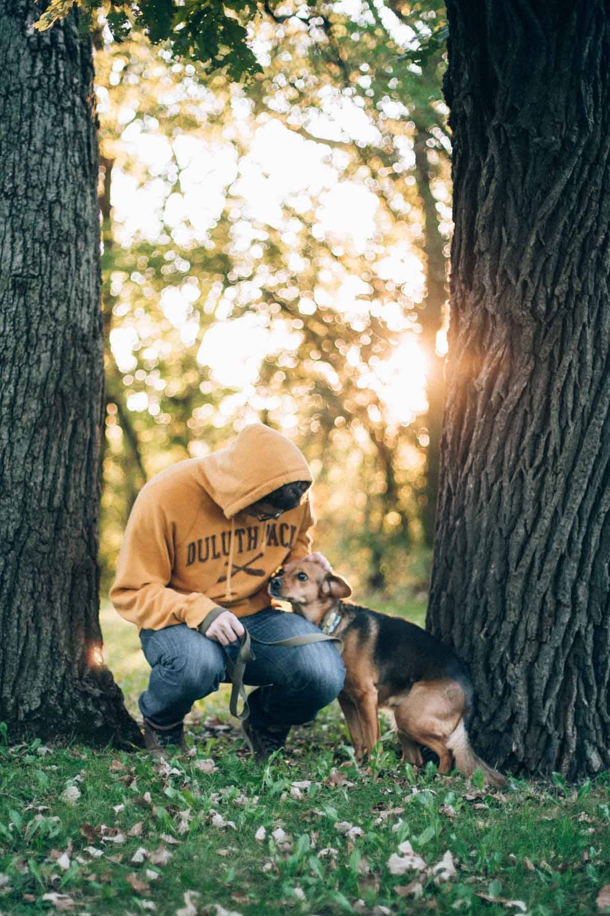 dog and man standing by two trees outside