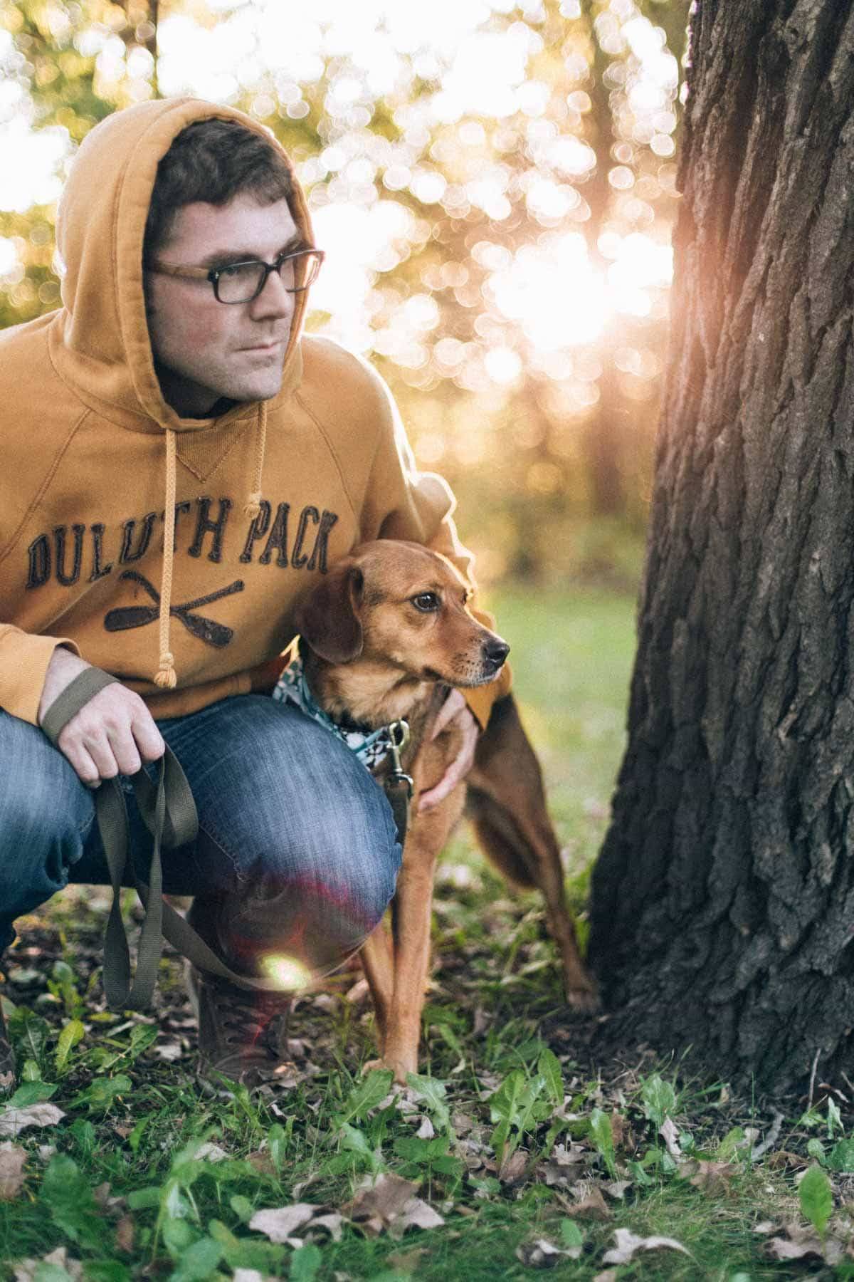 man and dog squatting outside