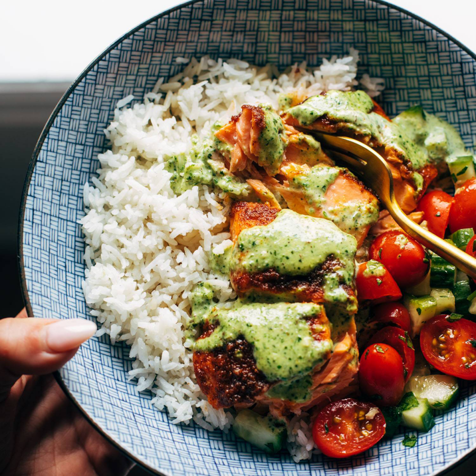 Salmon with basil sauce in a bowl with tomatoes and rice. 