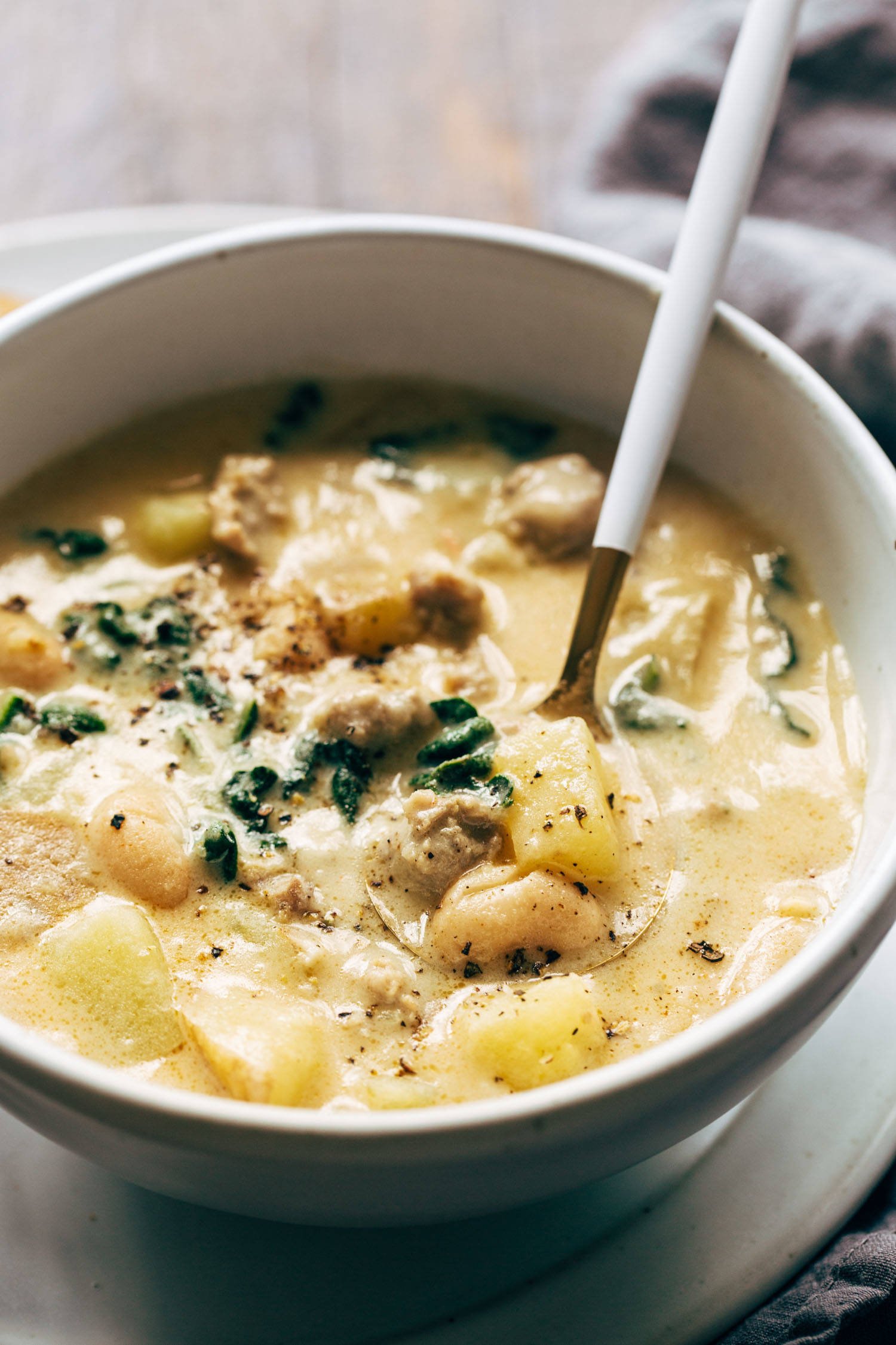 Sausage, kale, and bean soup in a bowl with a spoon.