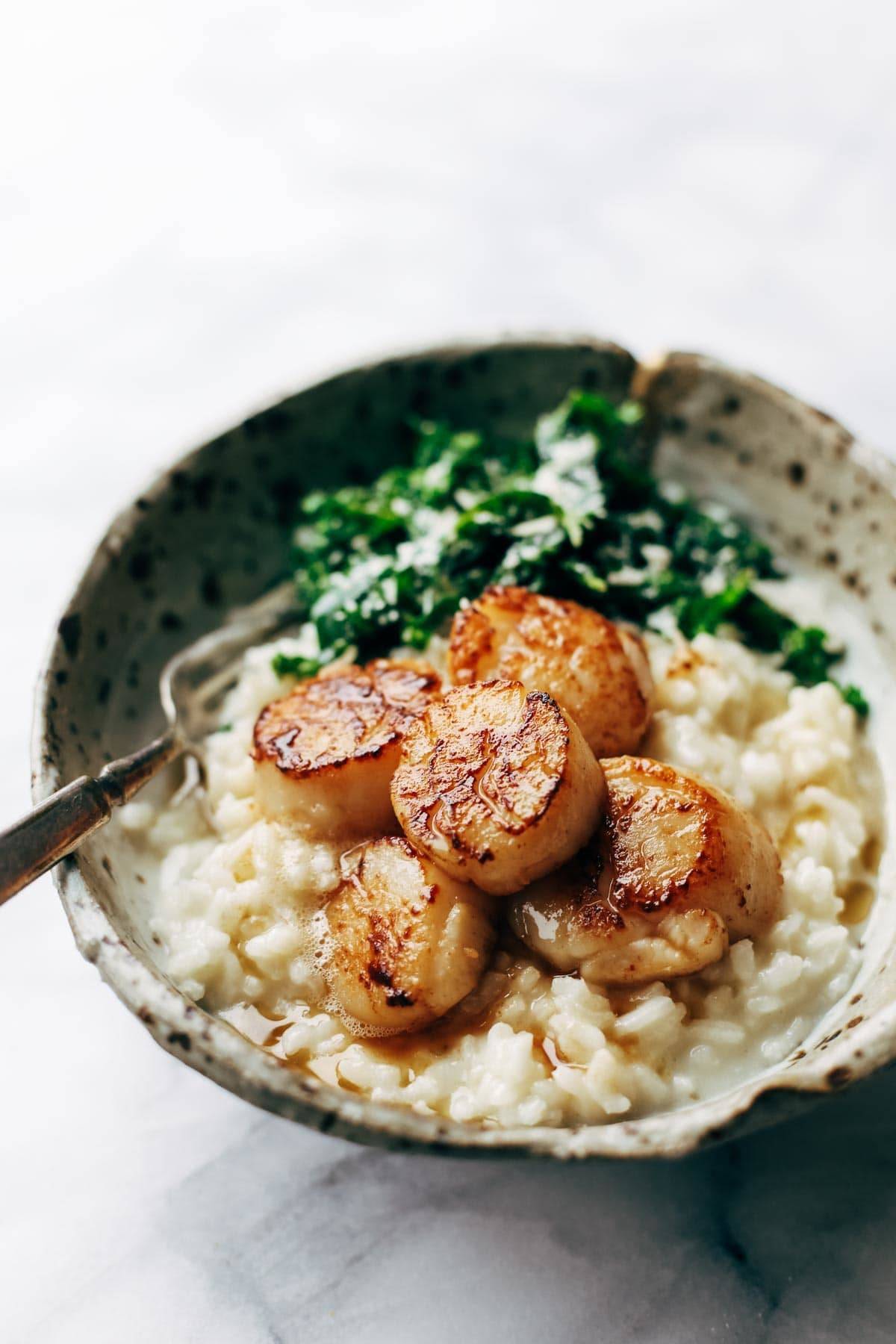 Brown butter scallops in a bowl with risotto and kale. 