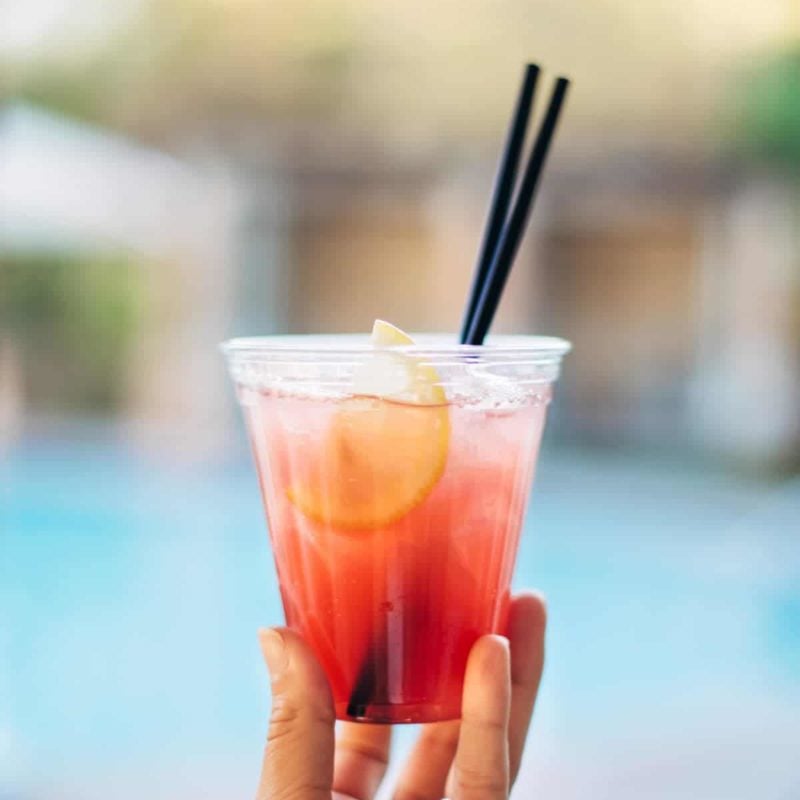 Hand holding a cocktail by the pool.