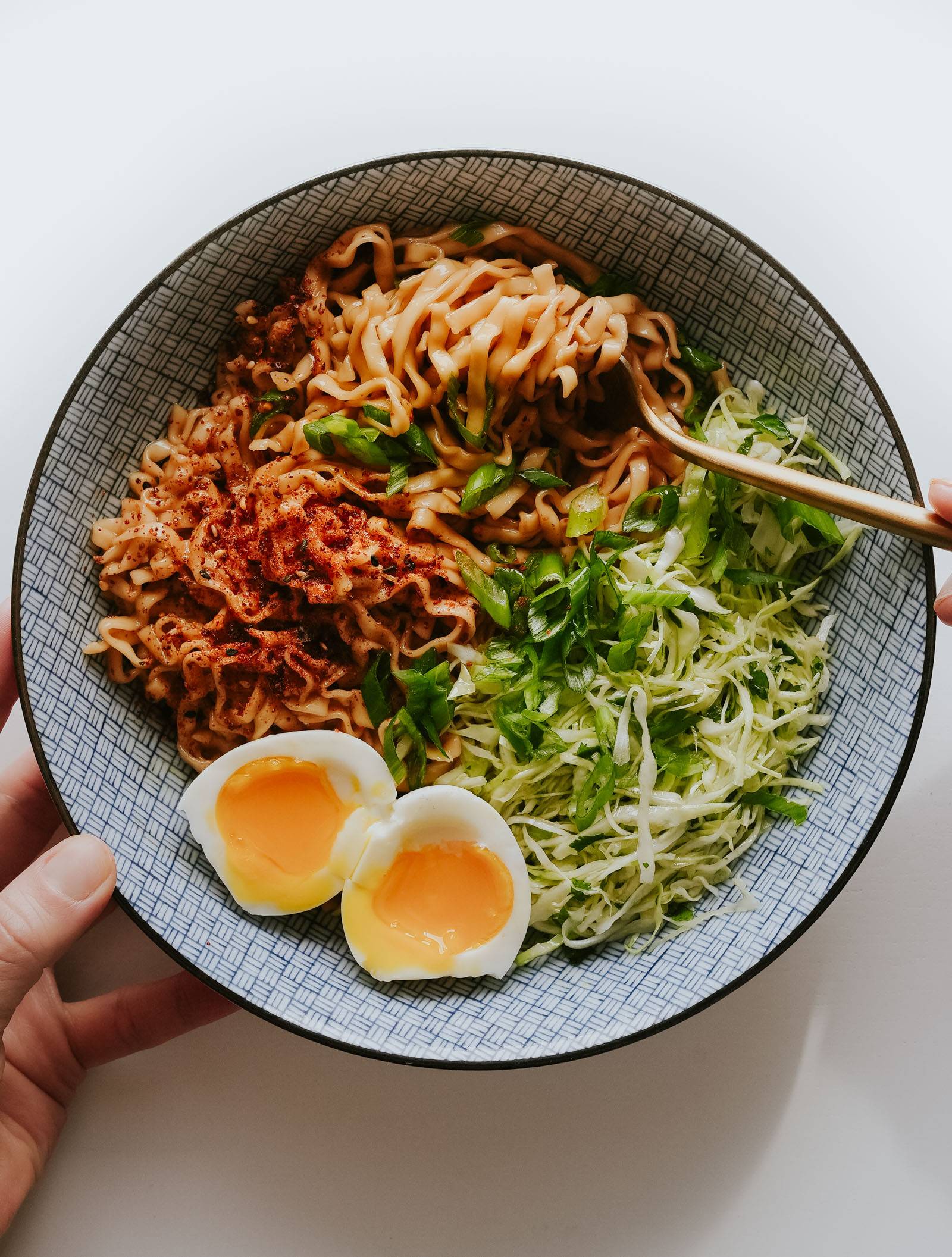 Sesame Butter Noodles in a bowl with a cabbage slaw and a soft boiled egg