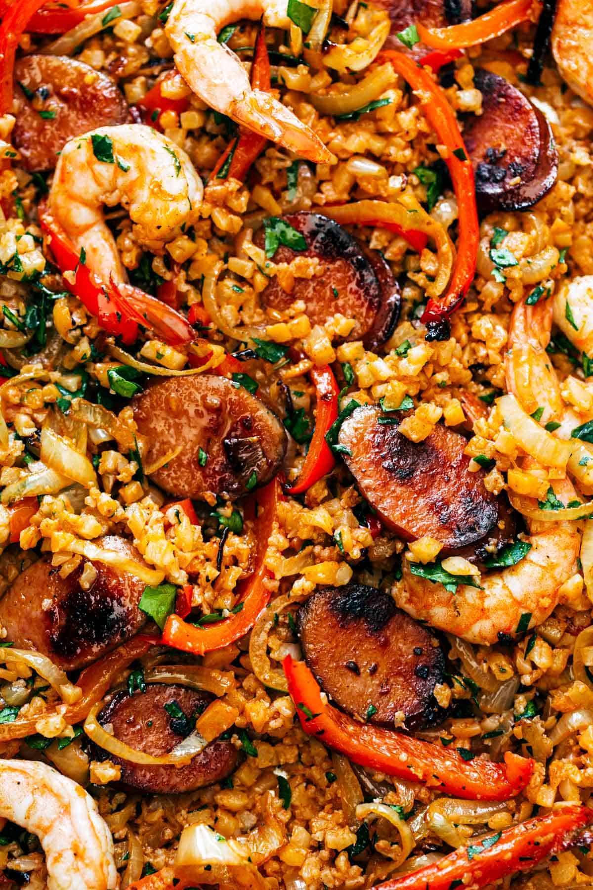 Cauliflower rice and meats arranged together on a sheet pan.