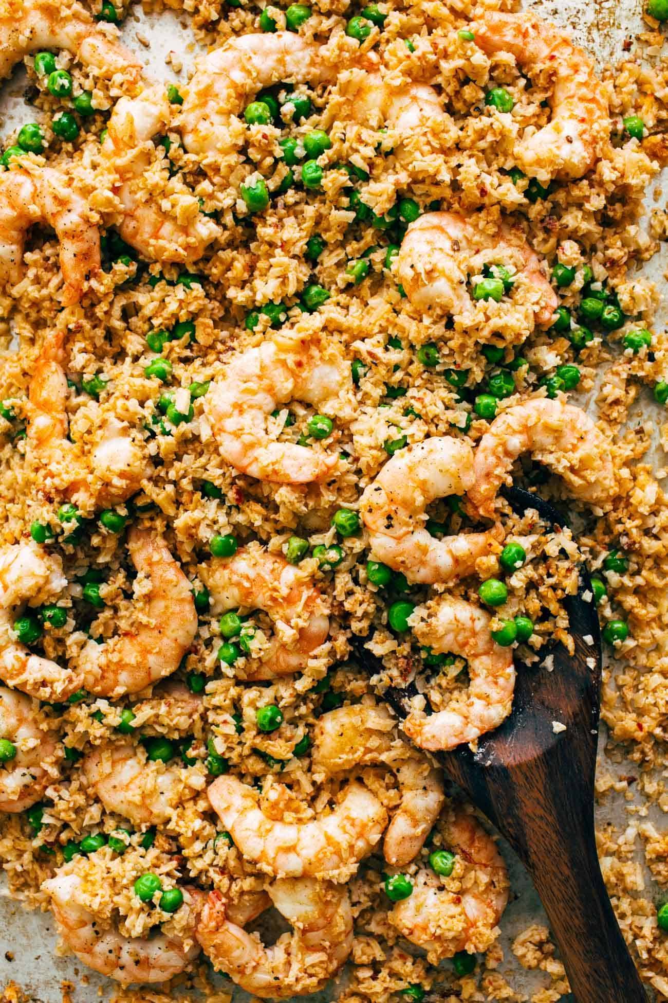 Cooked shrimp and cauliflower rice with peas on the sheet pan.