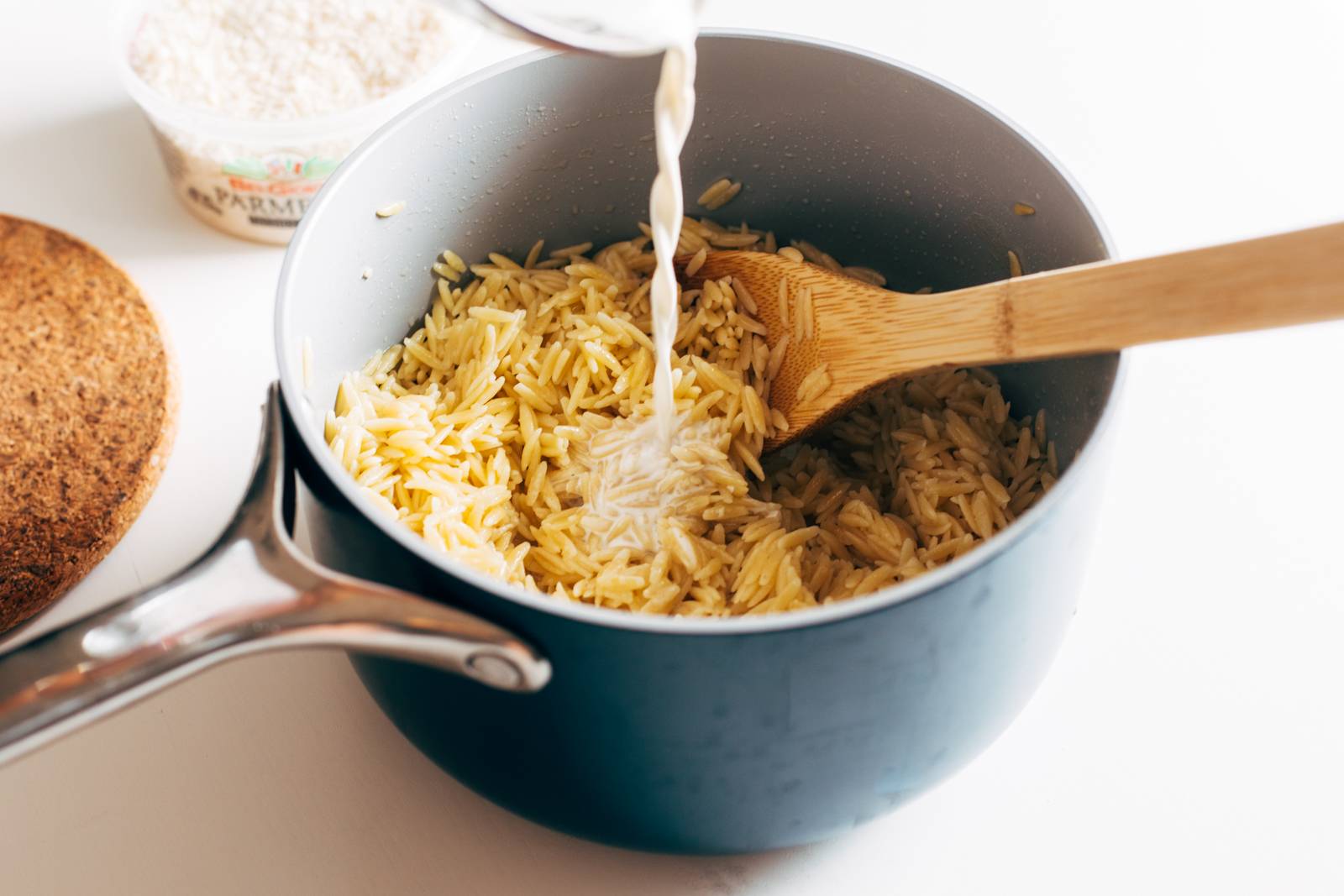 Creamy orzo in a pan with a wooden spoon