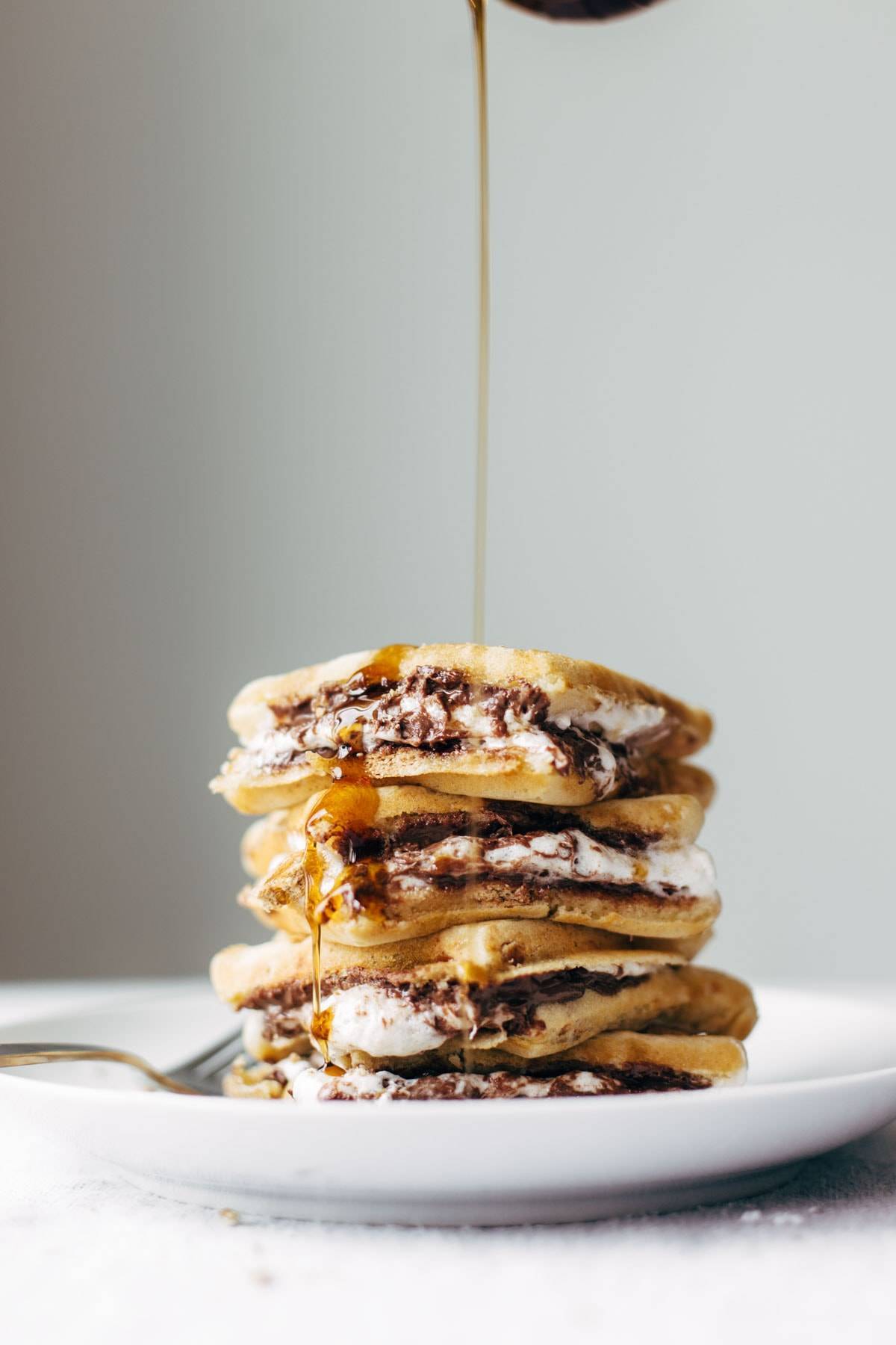 Smores Waffles with Nutella and Toasted Coconut on a plate with a syrup drizzle