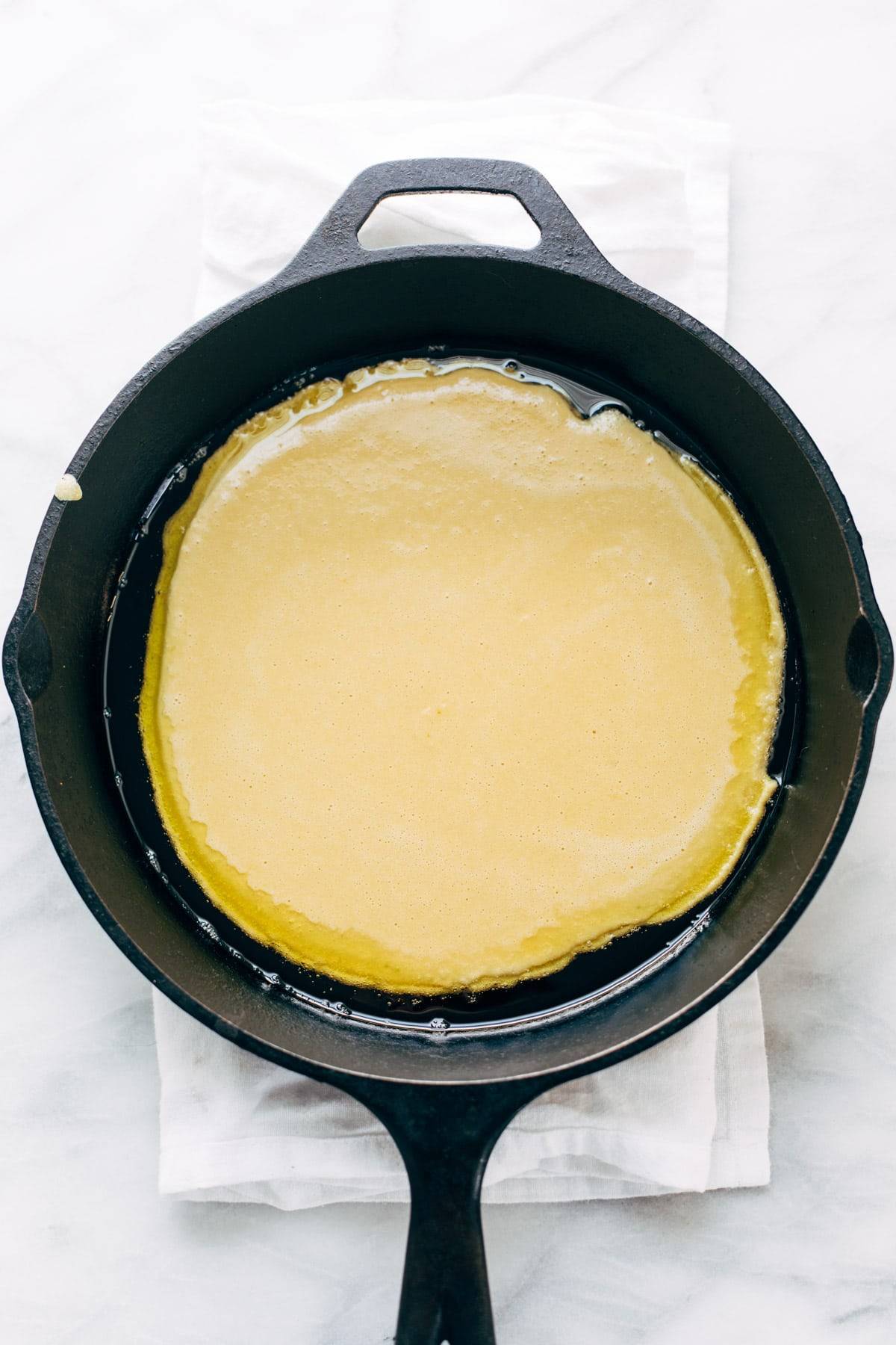 Socca batter in a cast iron pan.