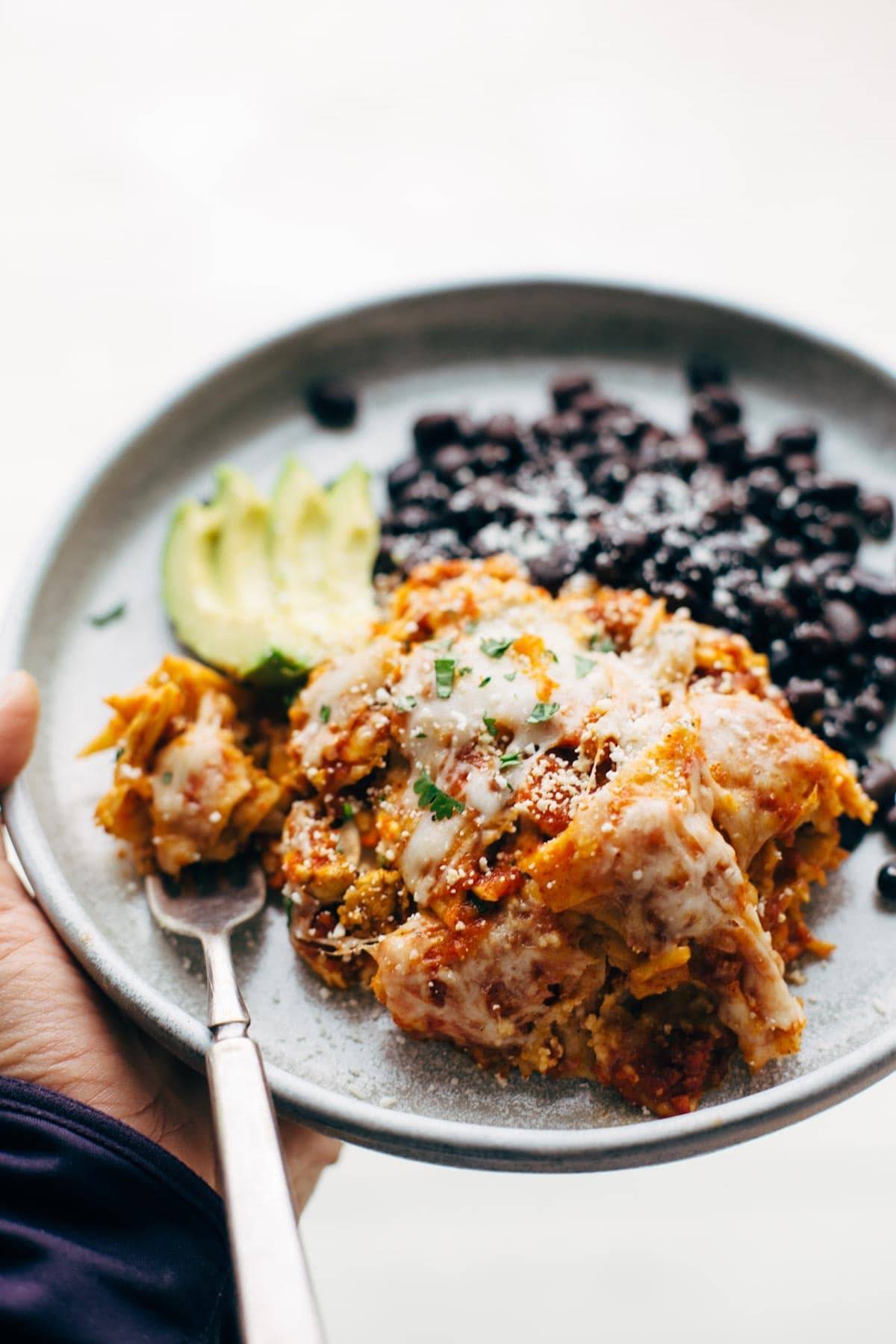Sofritas casserole with avocado and black beans on a plate with a fork.