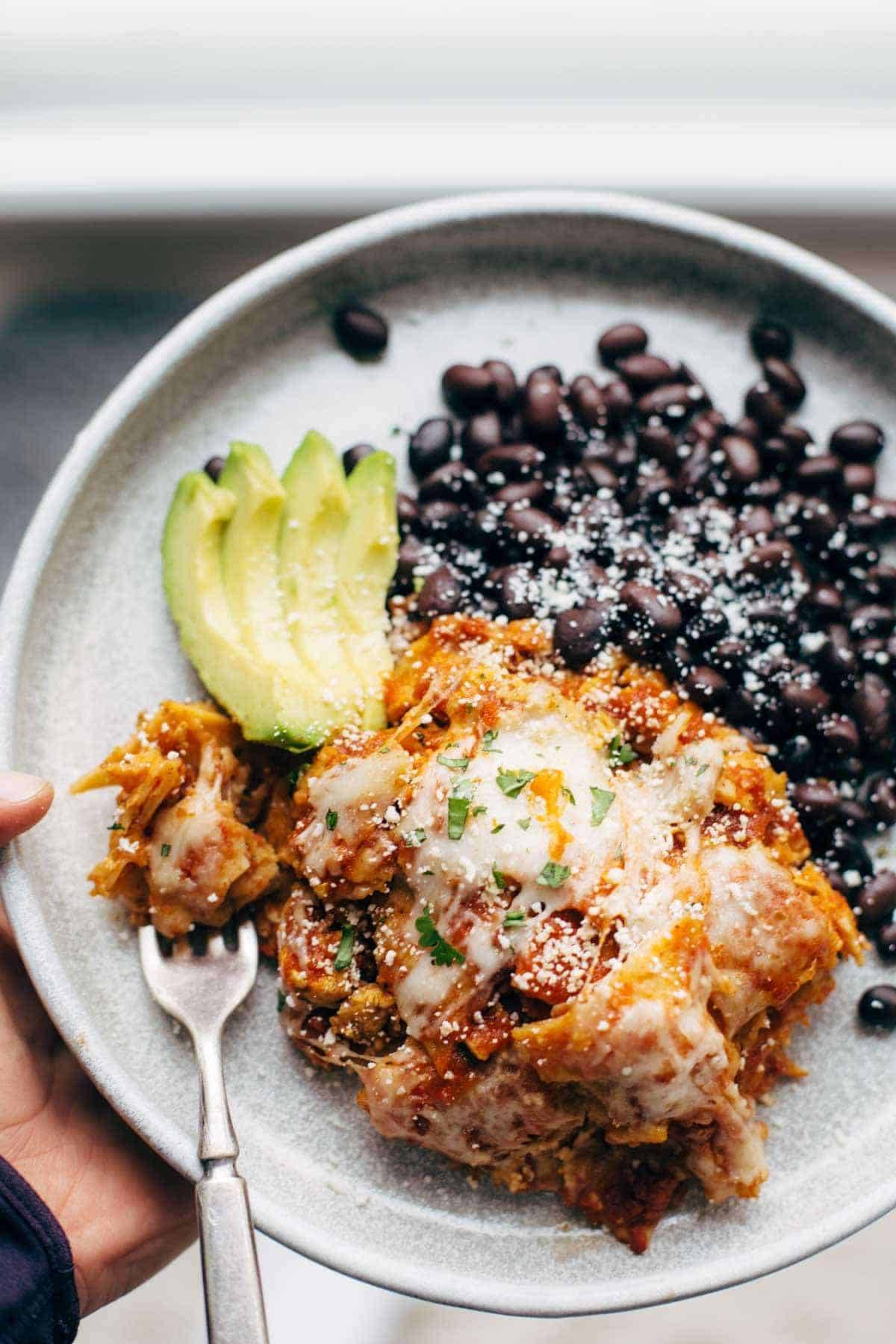 Sofritas casserole with avocado and black beans on a plate with a fork.