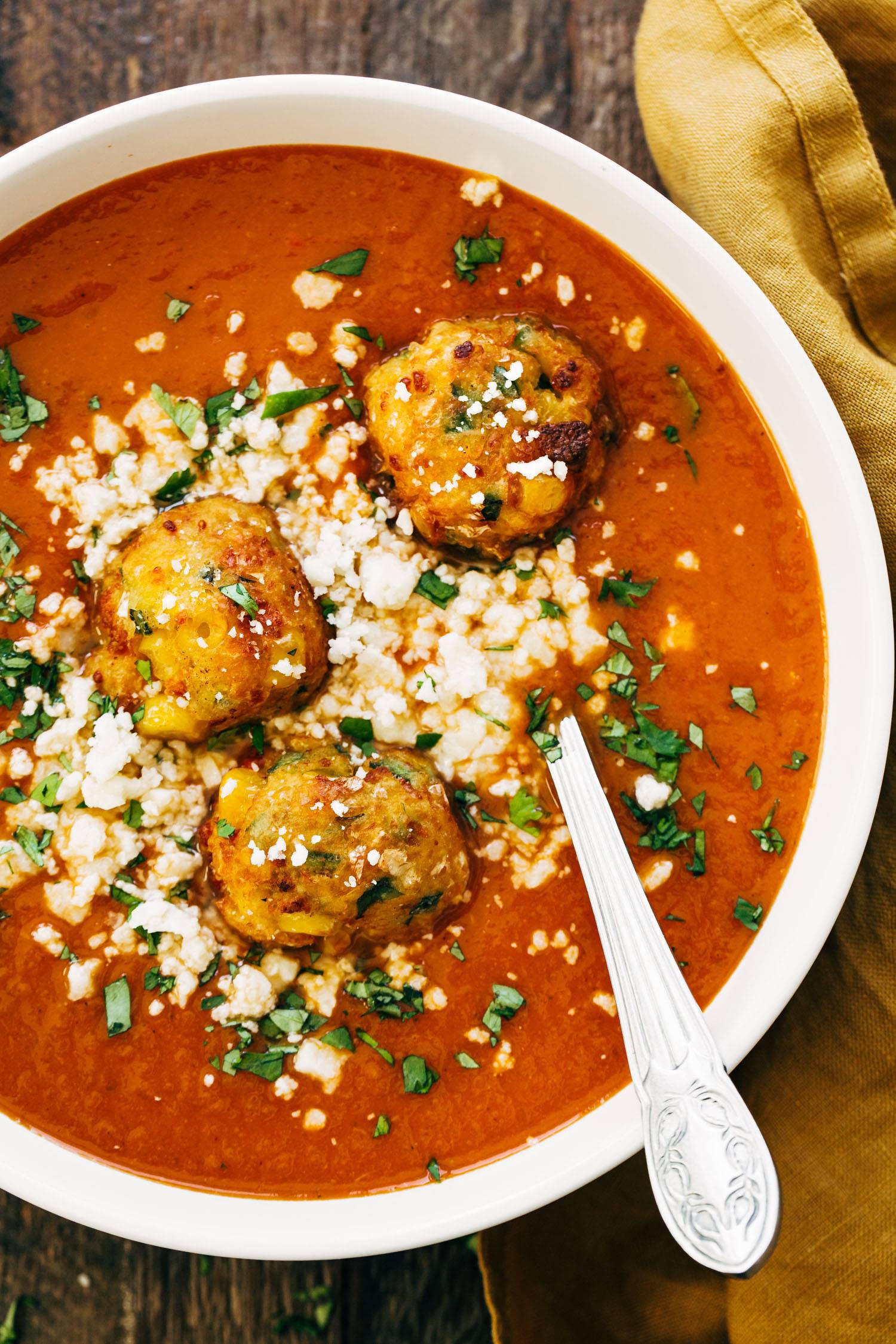 Sopa Tarasca in a bowl with a spoon and jalapeno corn fritters on top of the soup. 