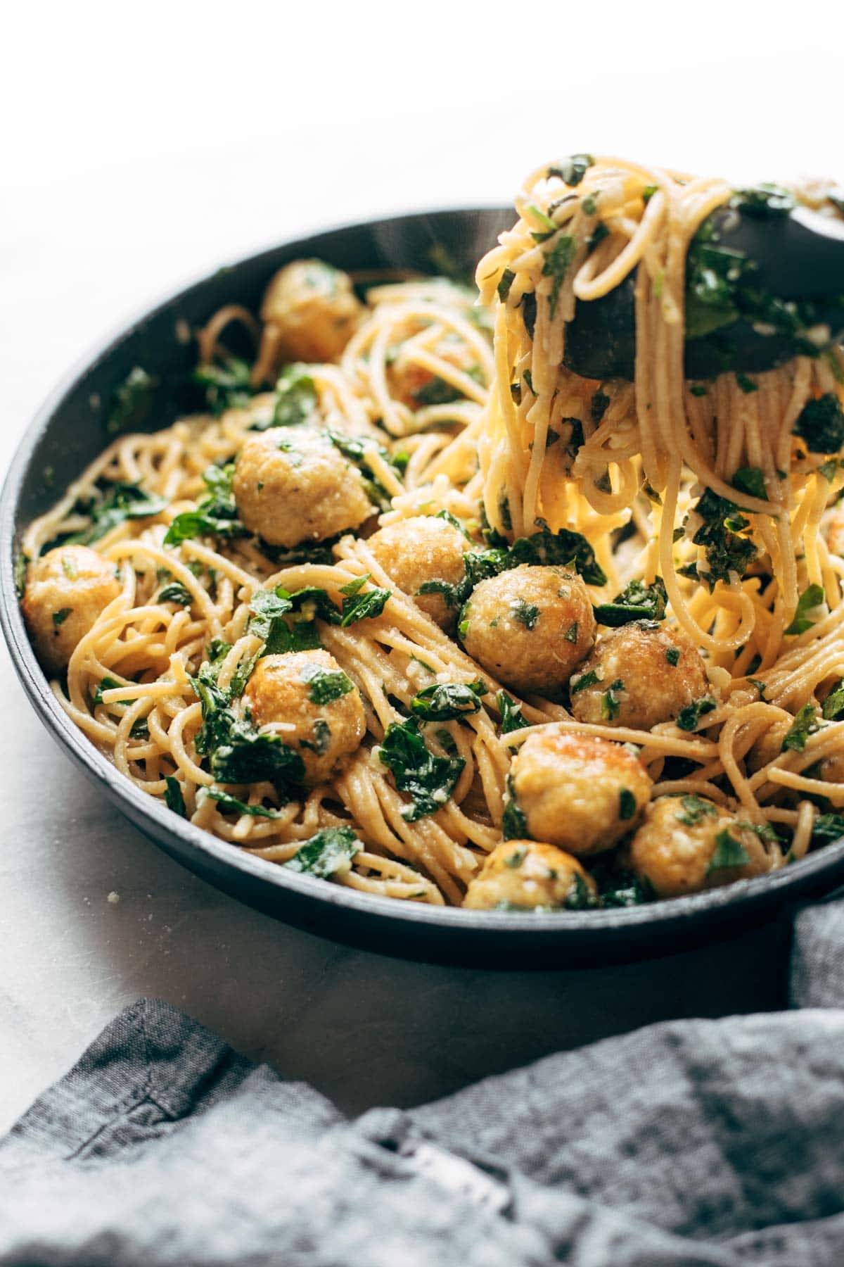 Garlic Herb Spaghetti with Baked Chicken Meatballs in a pan with noodle pull.