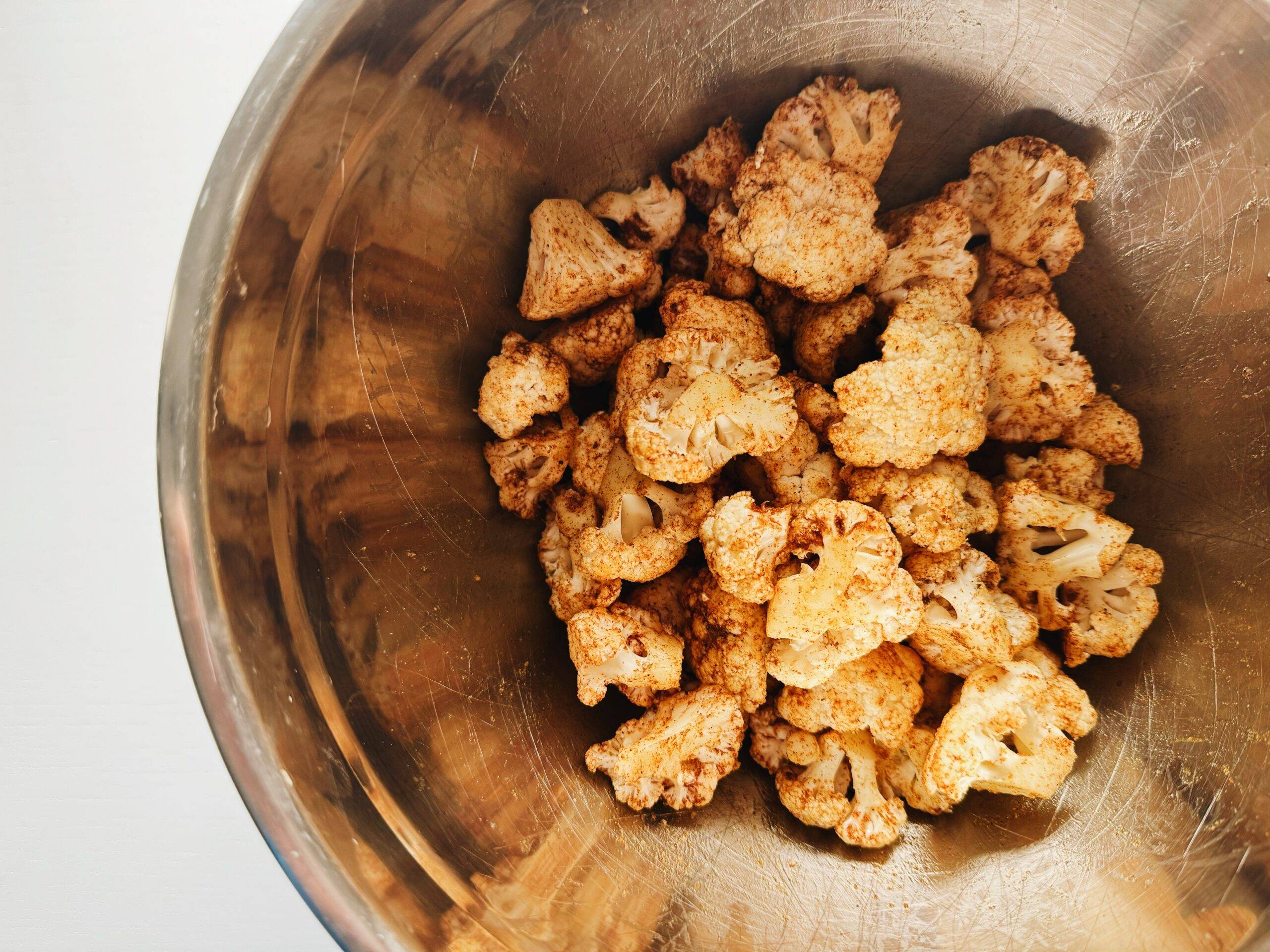Raw cauliflower in a bowl tossed in spices.
