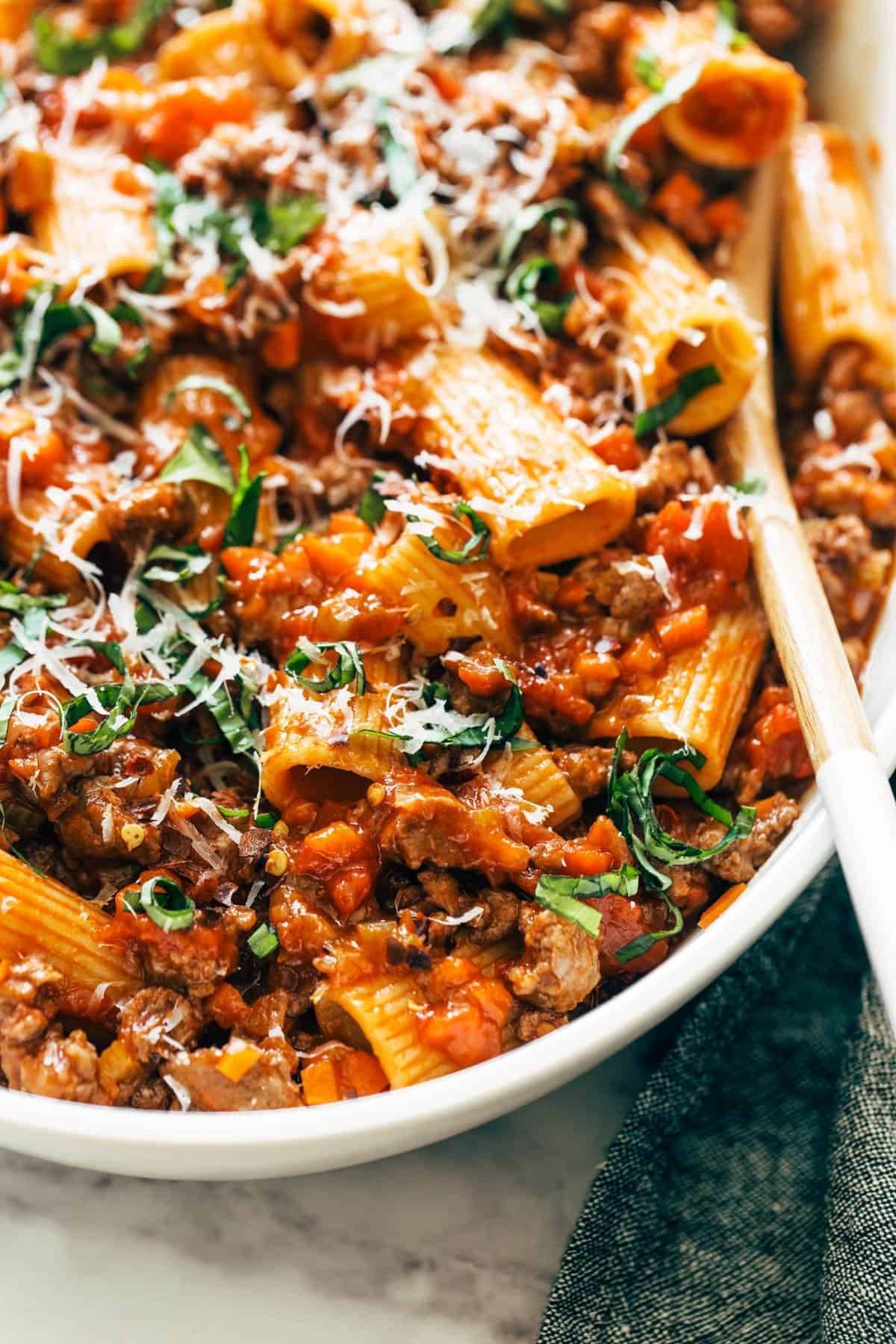 Spicy Sausage Rigatoni on a large serving bowl with a wooden spoon.