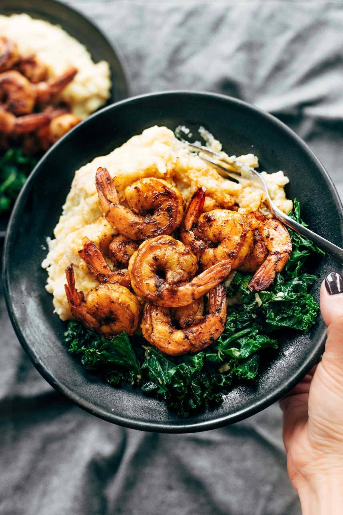 Spicy shrimp with cauliflower mash and kale on a plate.