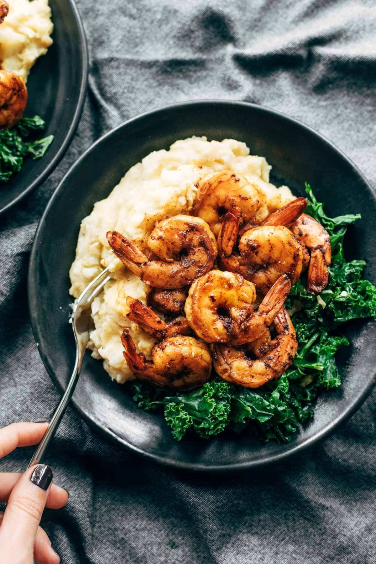 Spicy shrimp with cauliflower mash and kale on a plate with a fork.
