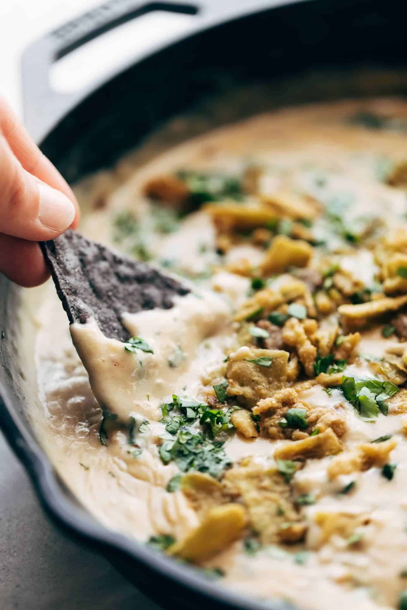 Tortilla chip dipping into Spinach Queso 