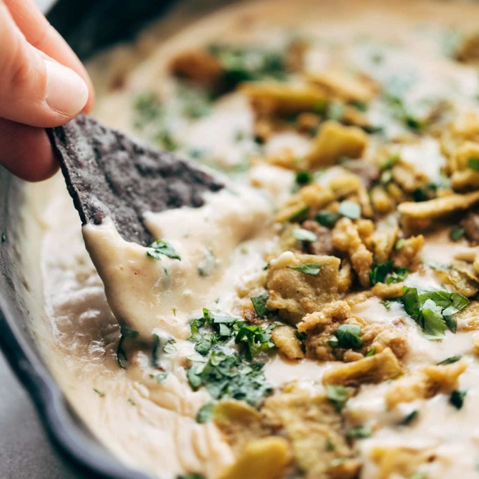 Spinach Queso in pan with chip dipping.